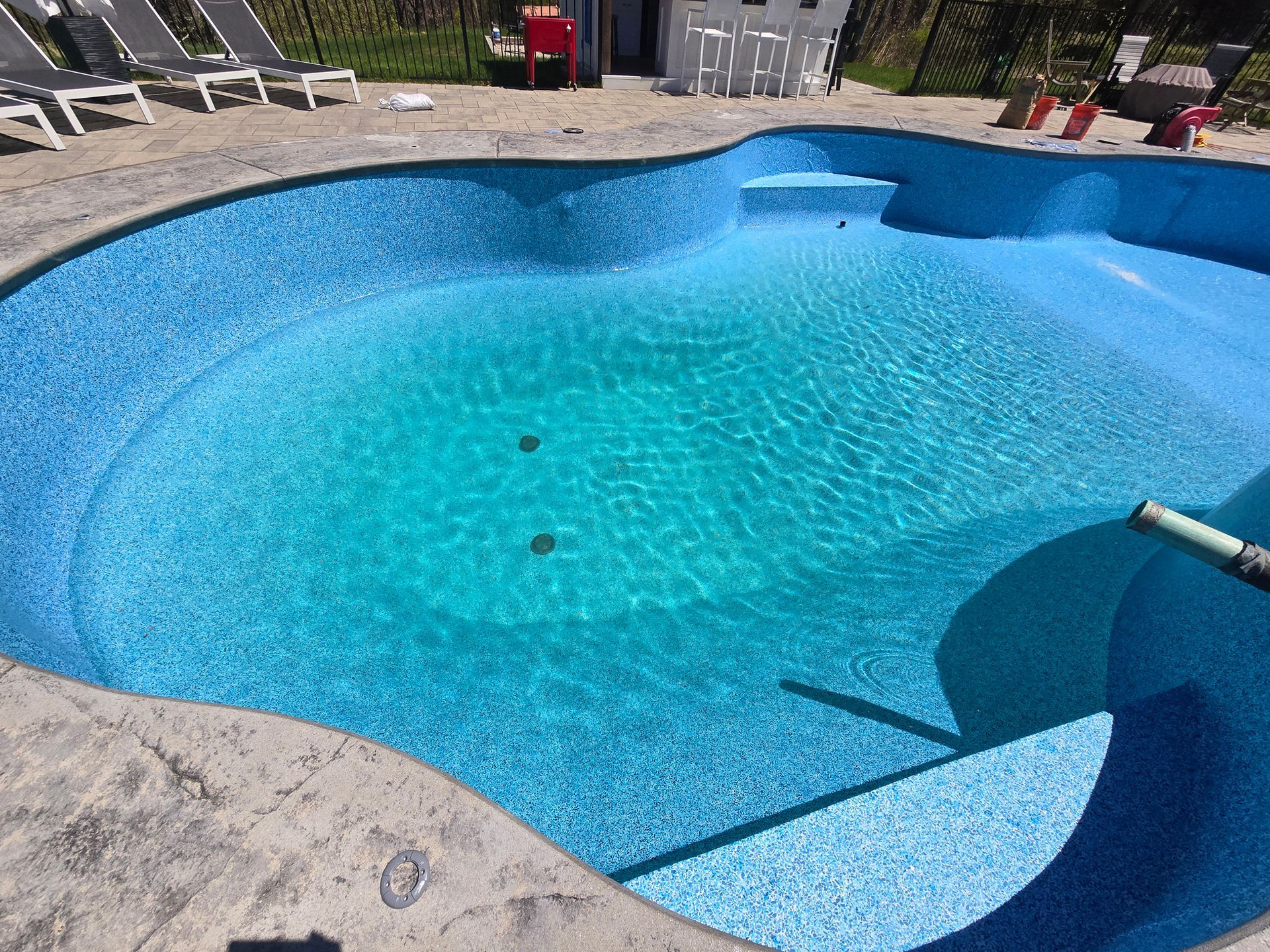 A large swimming pool with blue tiles and a hose in it.