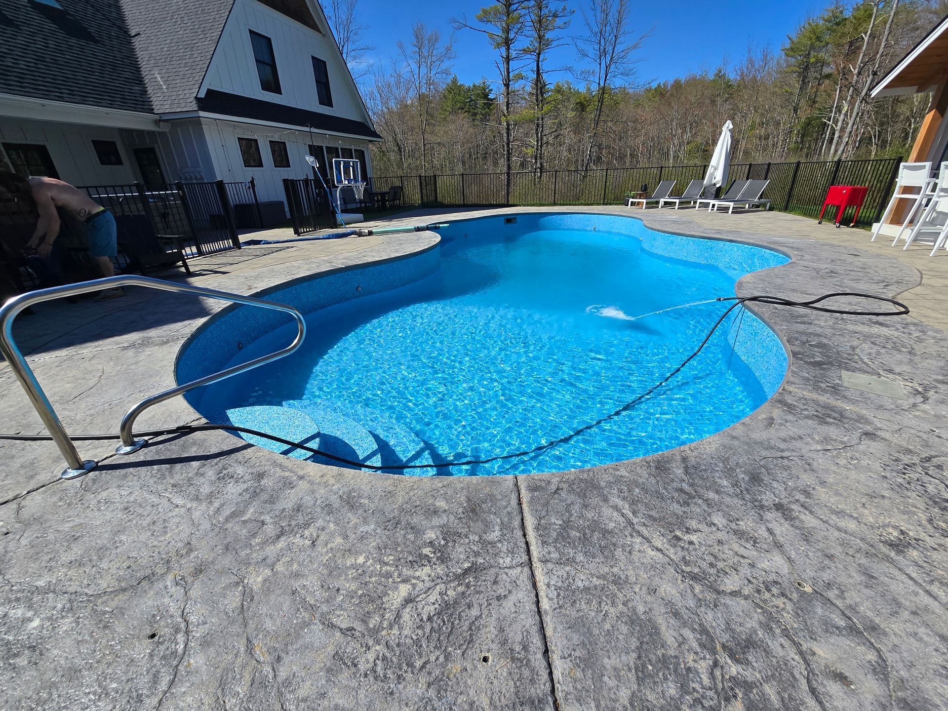 There is a large swimming pool in the backyard of a house.
