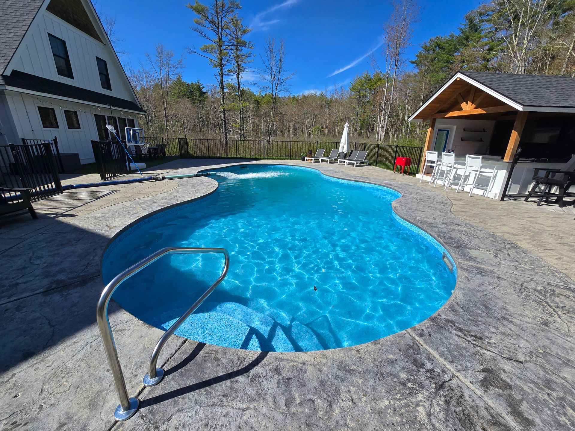 A large swimming pool with a staircase leading to it in front of a house.