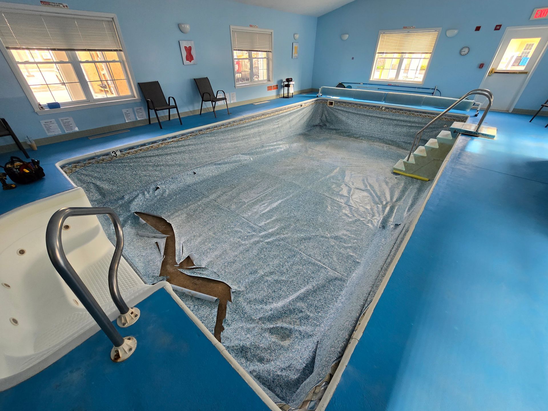 An empty swimming pool in a room with blue walls