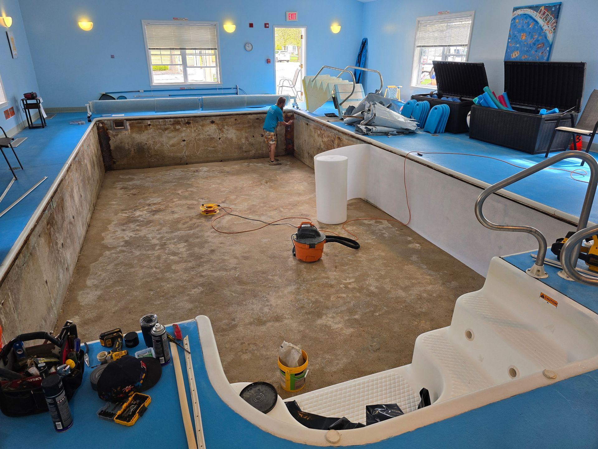 A large swimming pool is being remodeled in a room.