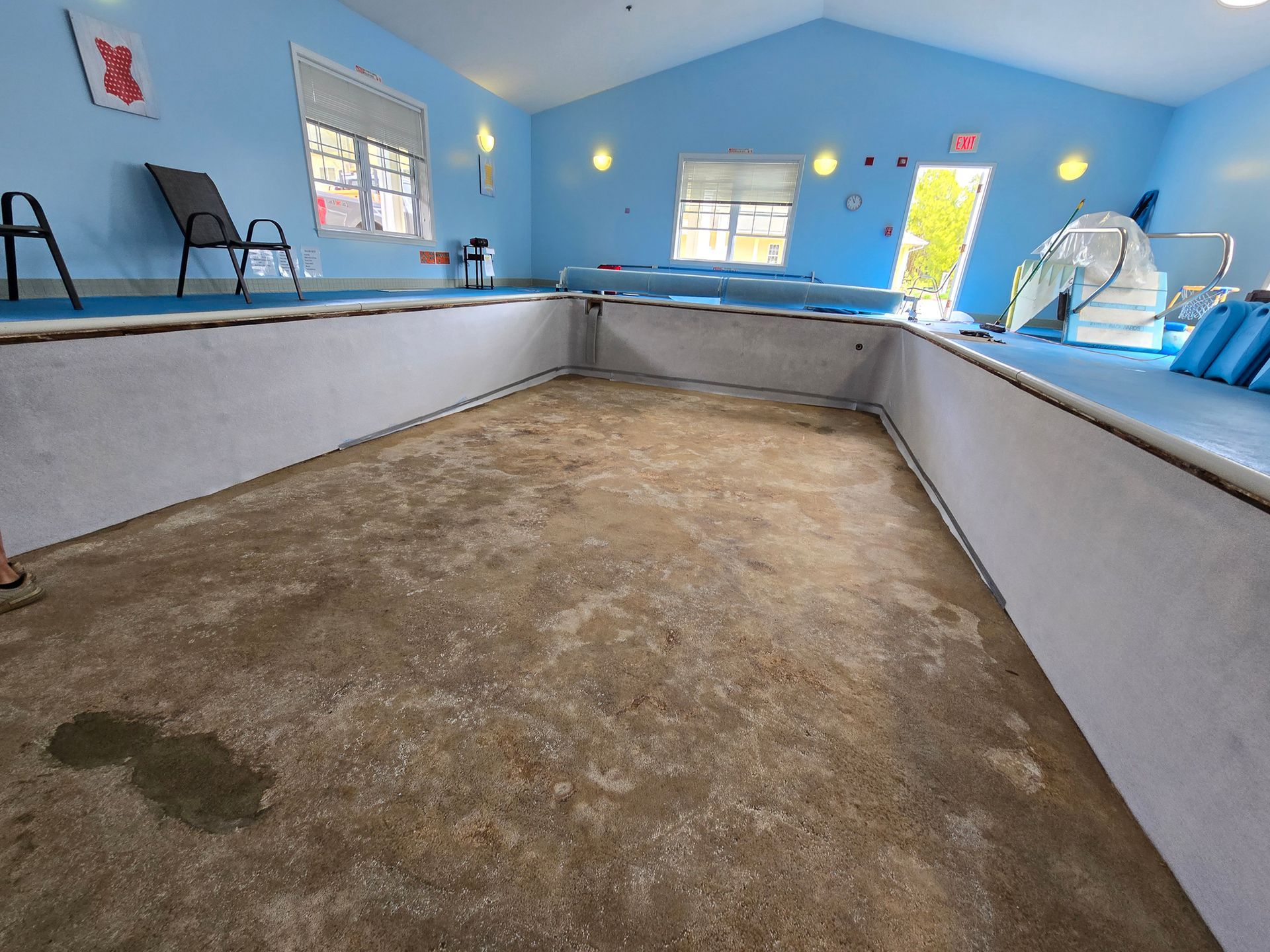 A large indoor swimming pool with blue walls and chairs