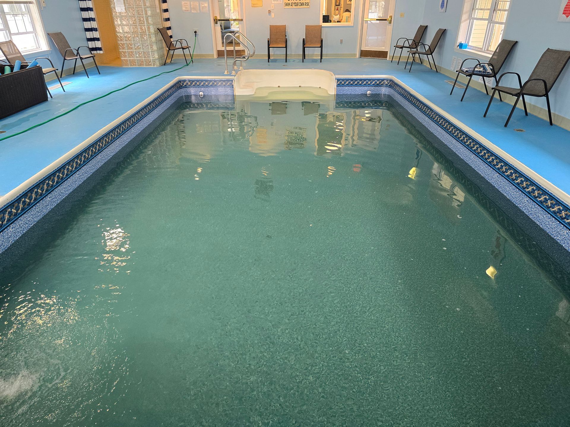 A large indoor swimming pool with chairs around it