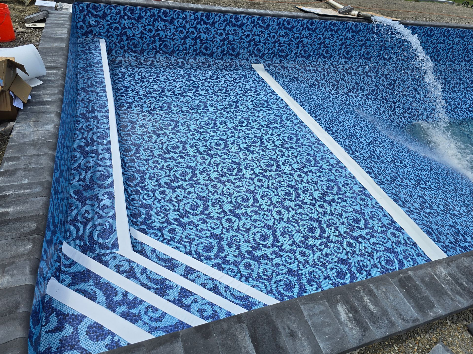 A swimming pool is being built with blue tiles and white stripes