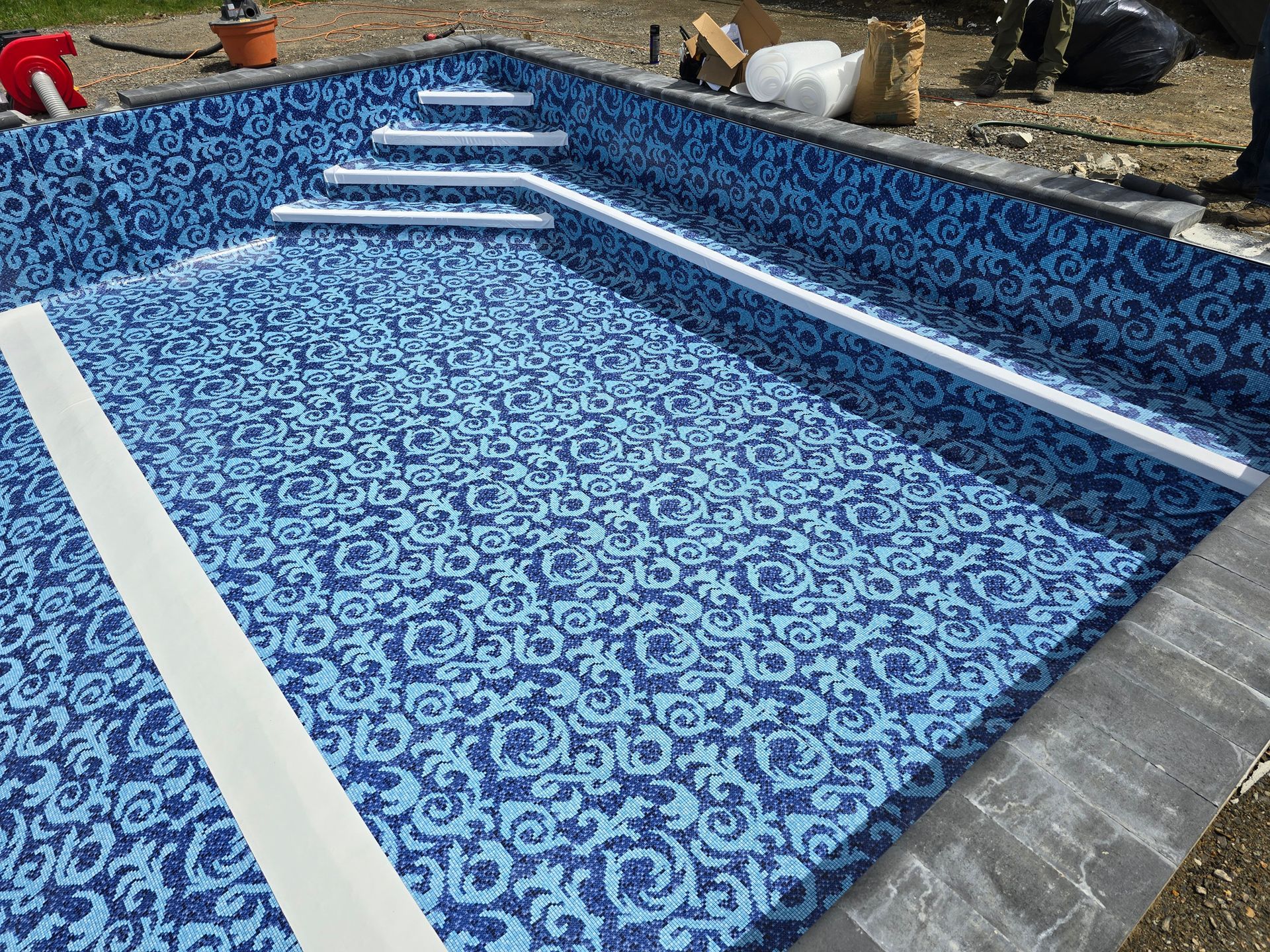 A swimming pool is being built with blue tiles and stairs.