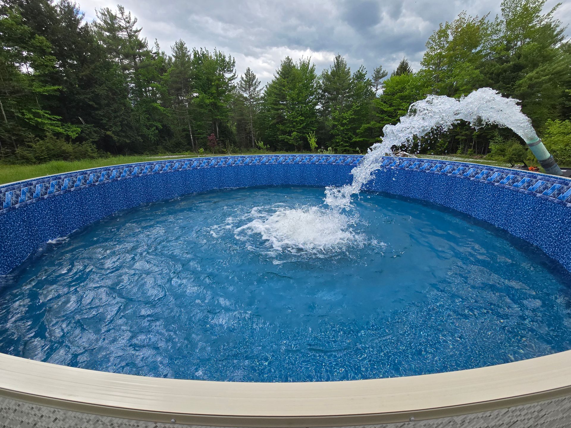 A swimming pool with a fountain in the middle of it.