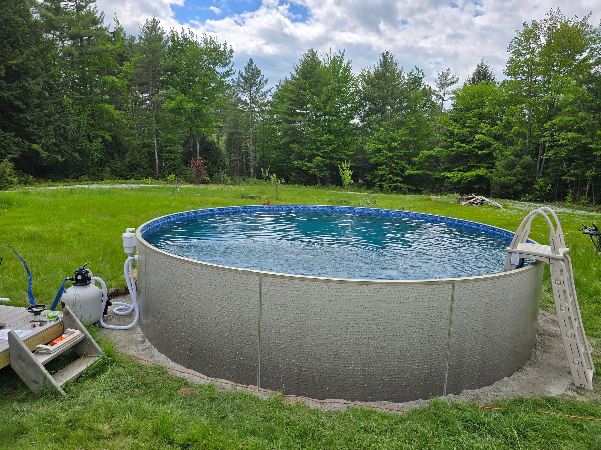 A large swimming pool is sitting in the middle of a lush green field.