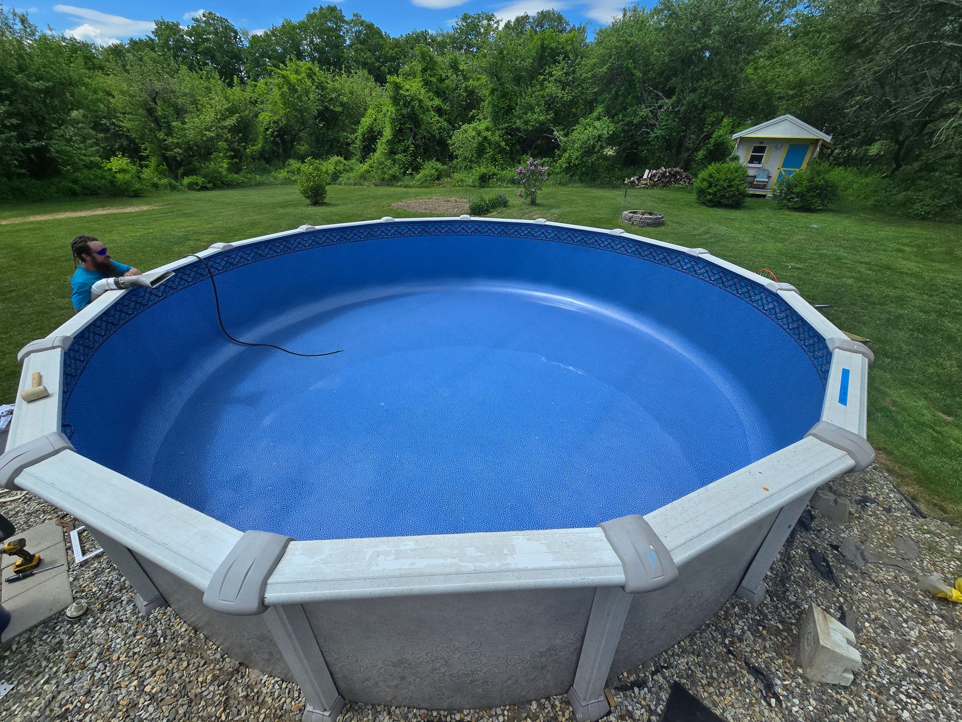 A man is working on a swimming pool in a backyard.