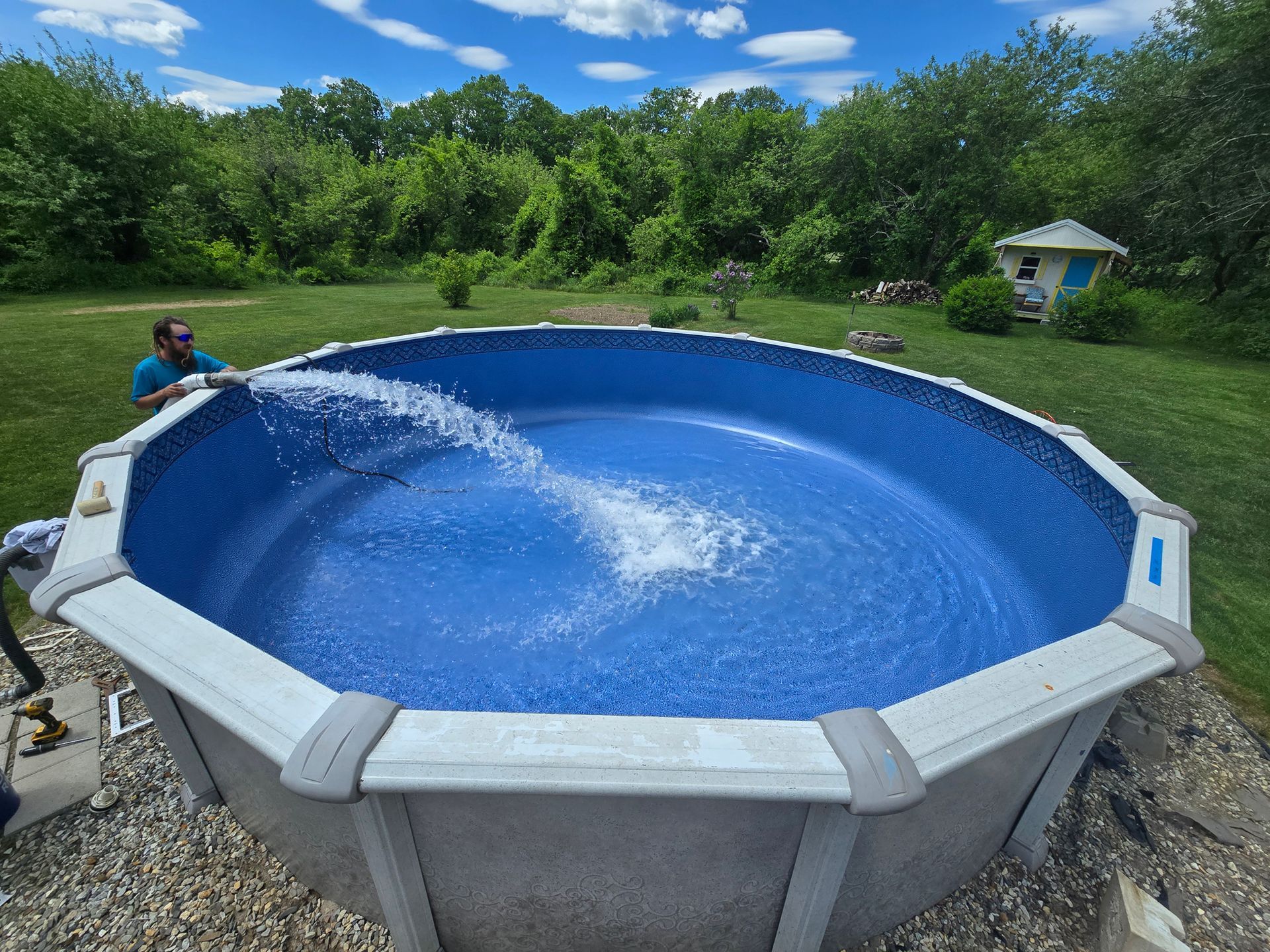 A man is pumping water into a swimming pool.