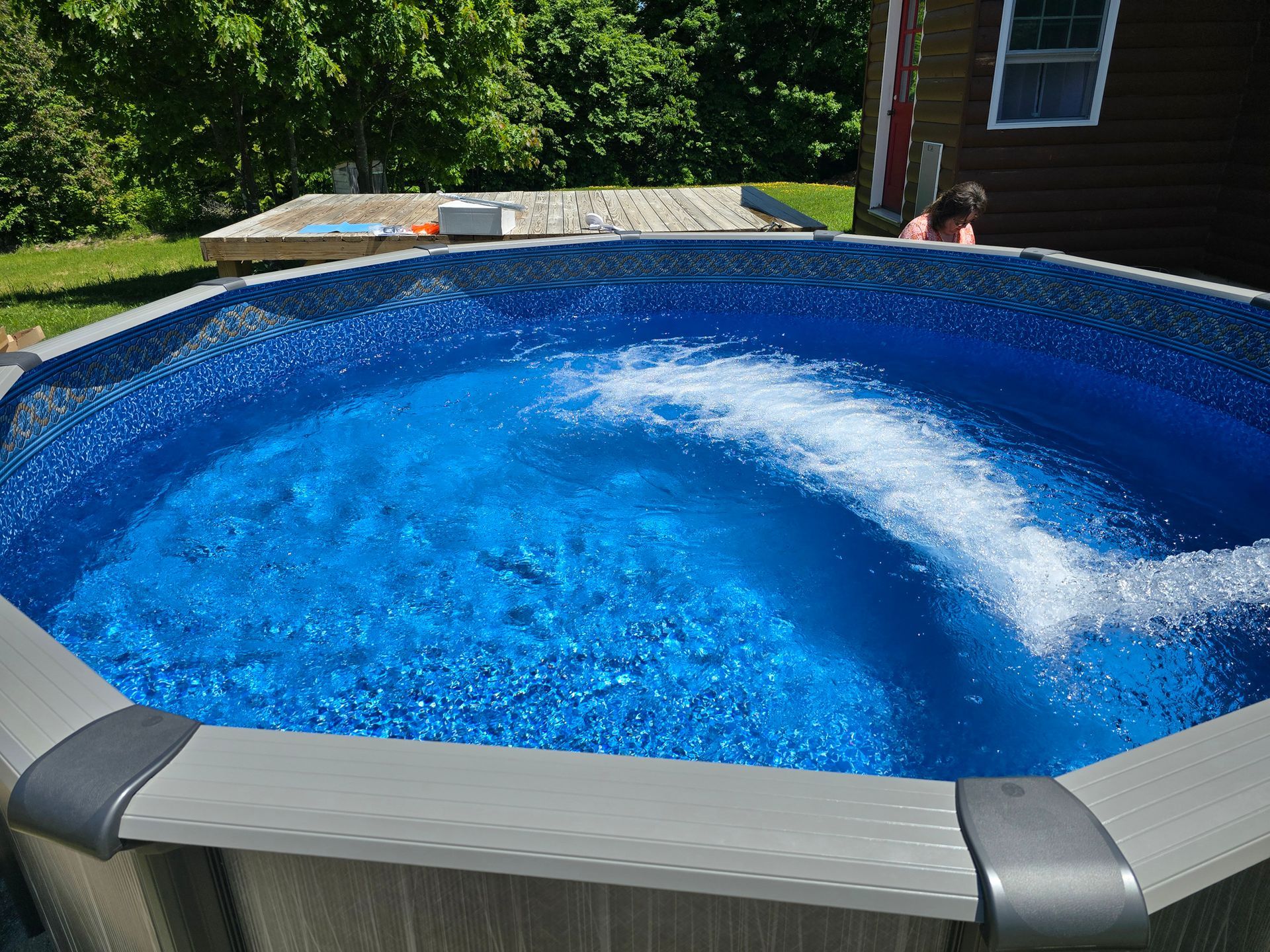 A large swimming pool with blue water is being filled with water.