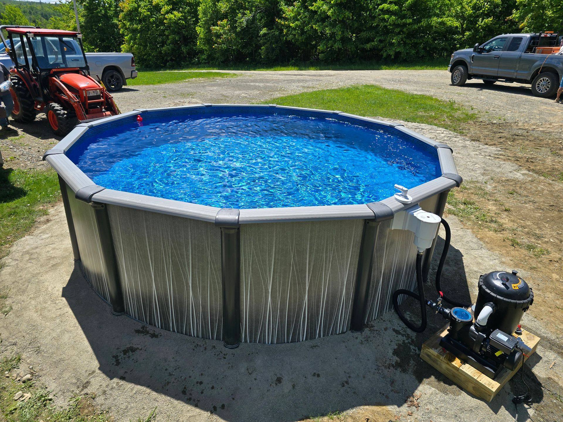 A large swimming pool filled with blue water and a tractor parked in the background.