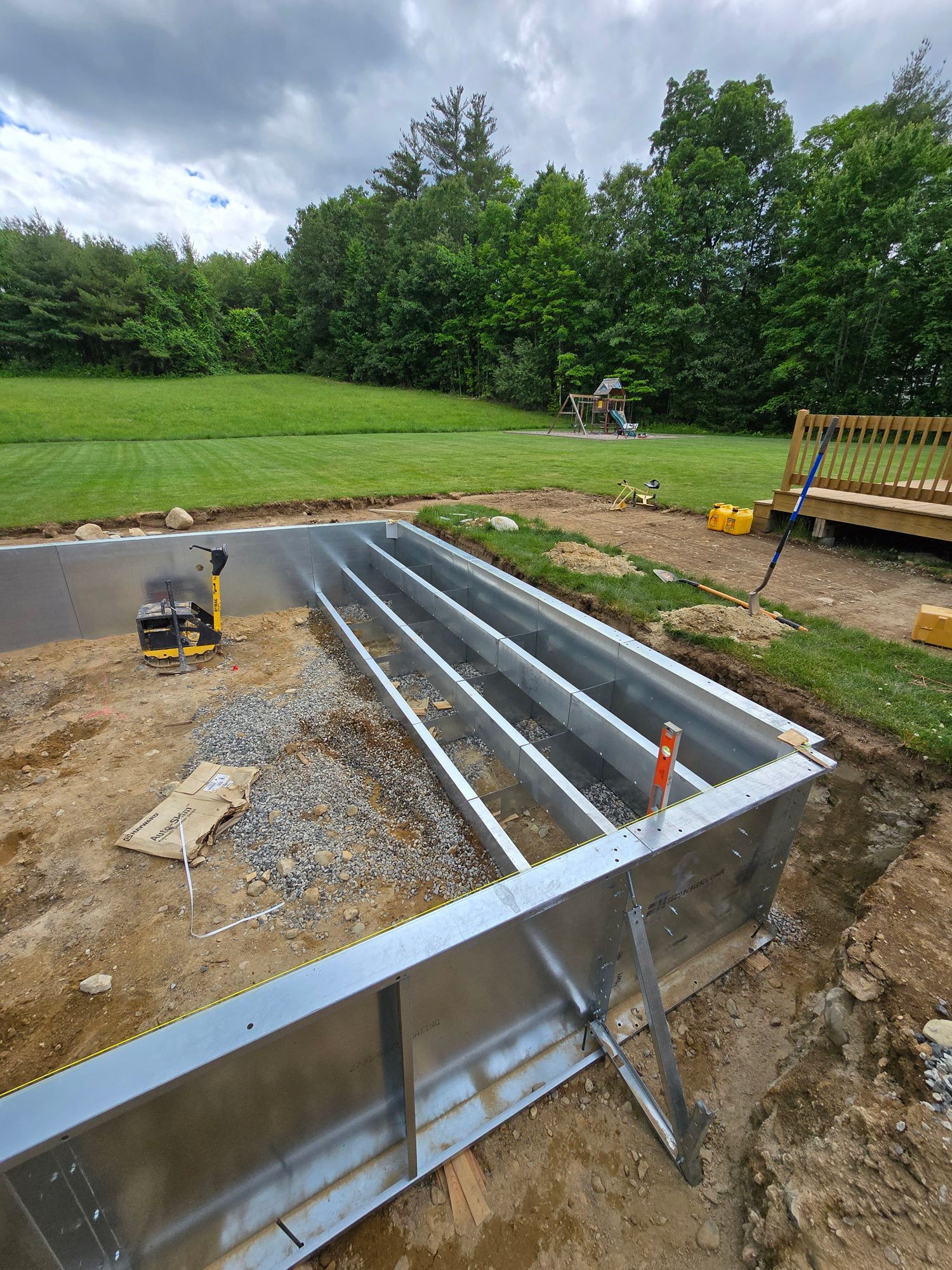 A metal structure is being built in the dirt in a backyard.
