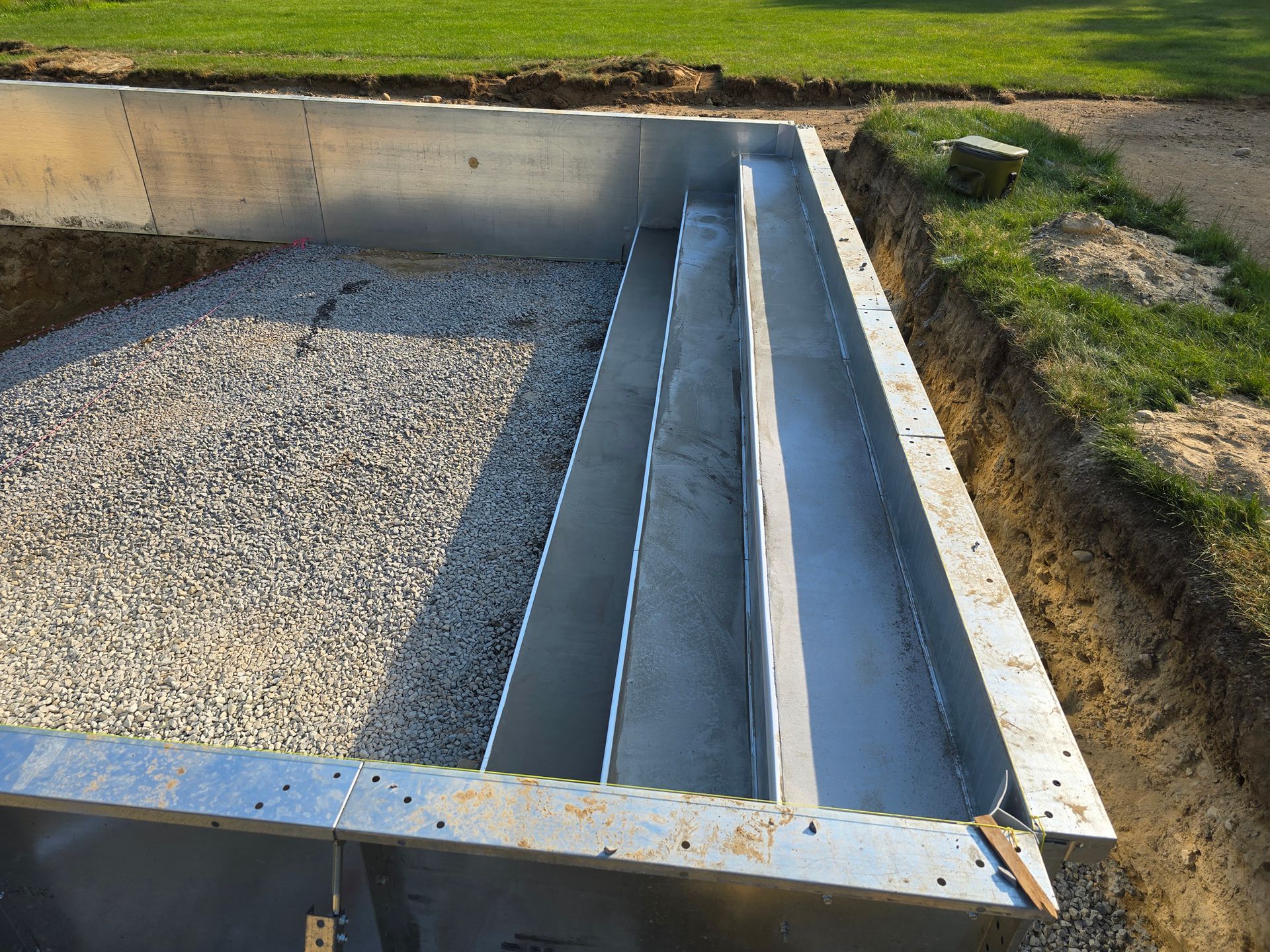 A metal structure is sitting in the dirt next to a grassy field