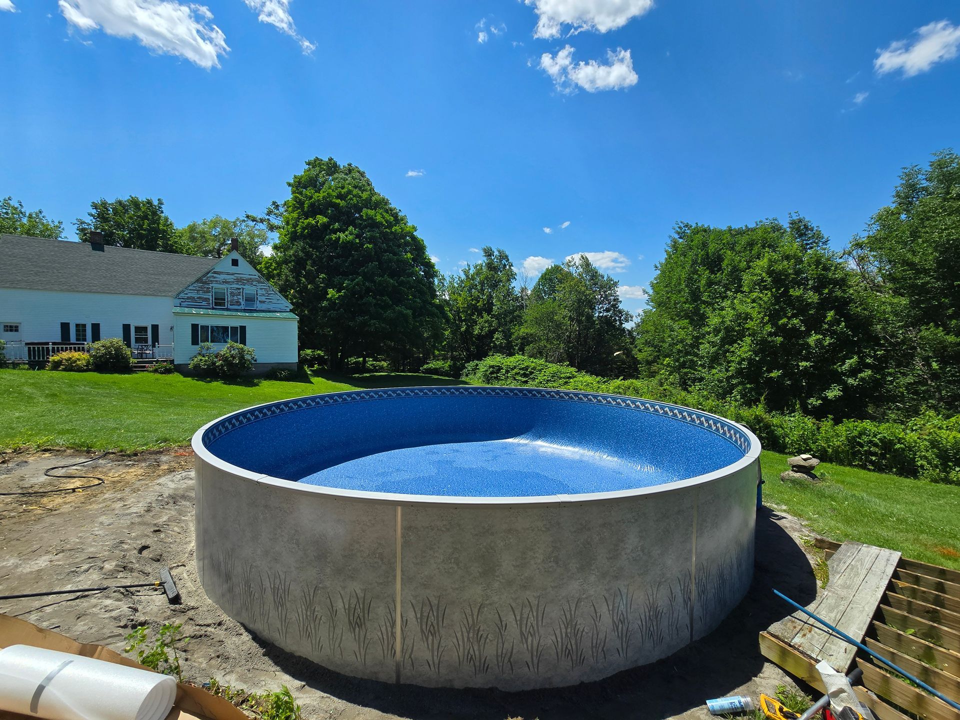 A large swimming pool is being built in the backyard of a house.