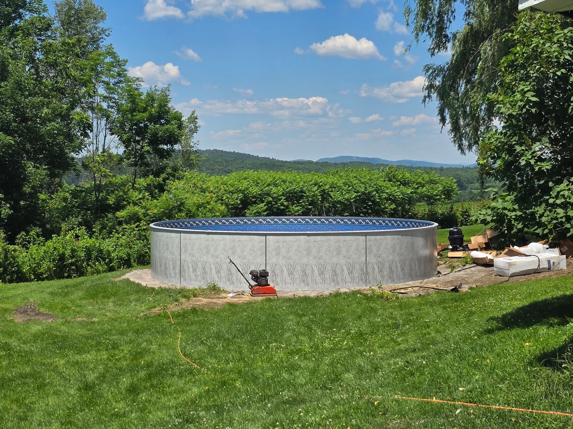 A large swimming pool is sitting in the middle of a lush green field.