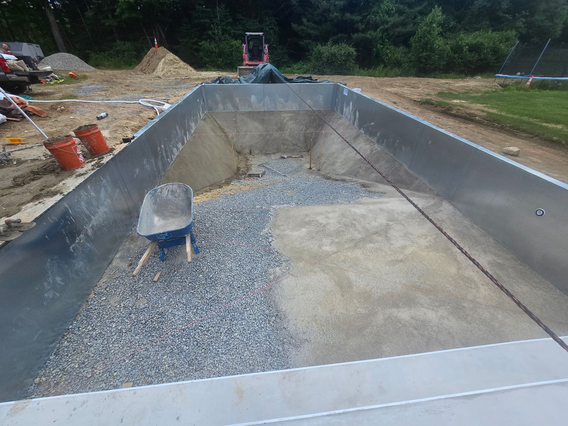 A wheelbarrow is sitting in the middle of a large metal container filled with gravel.