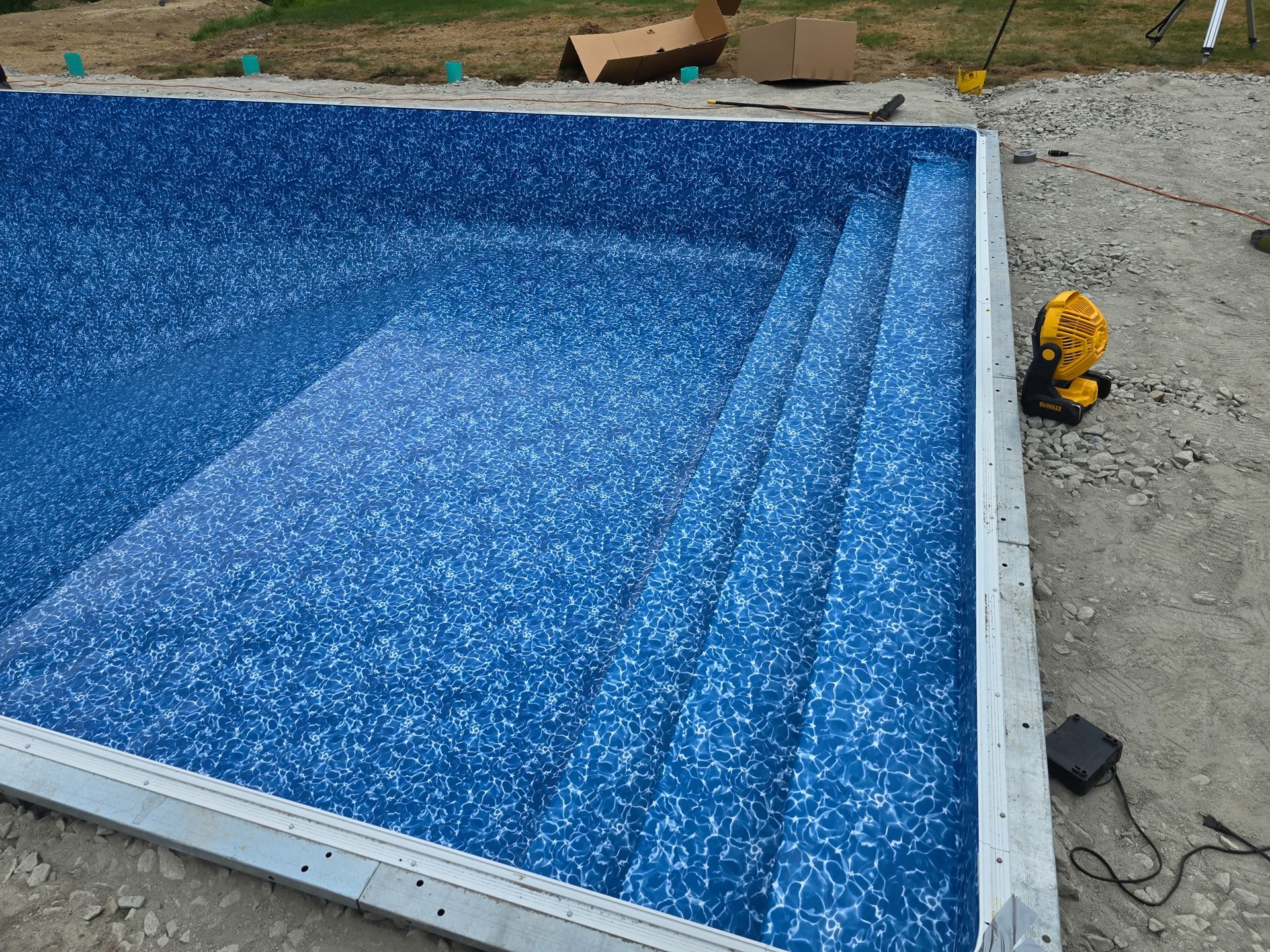 A swimming pool is being built with blue tiles and stairs.