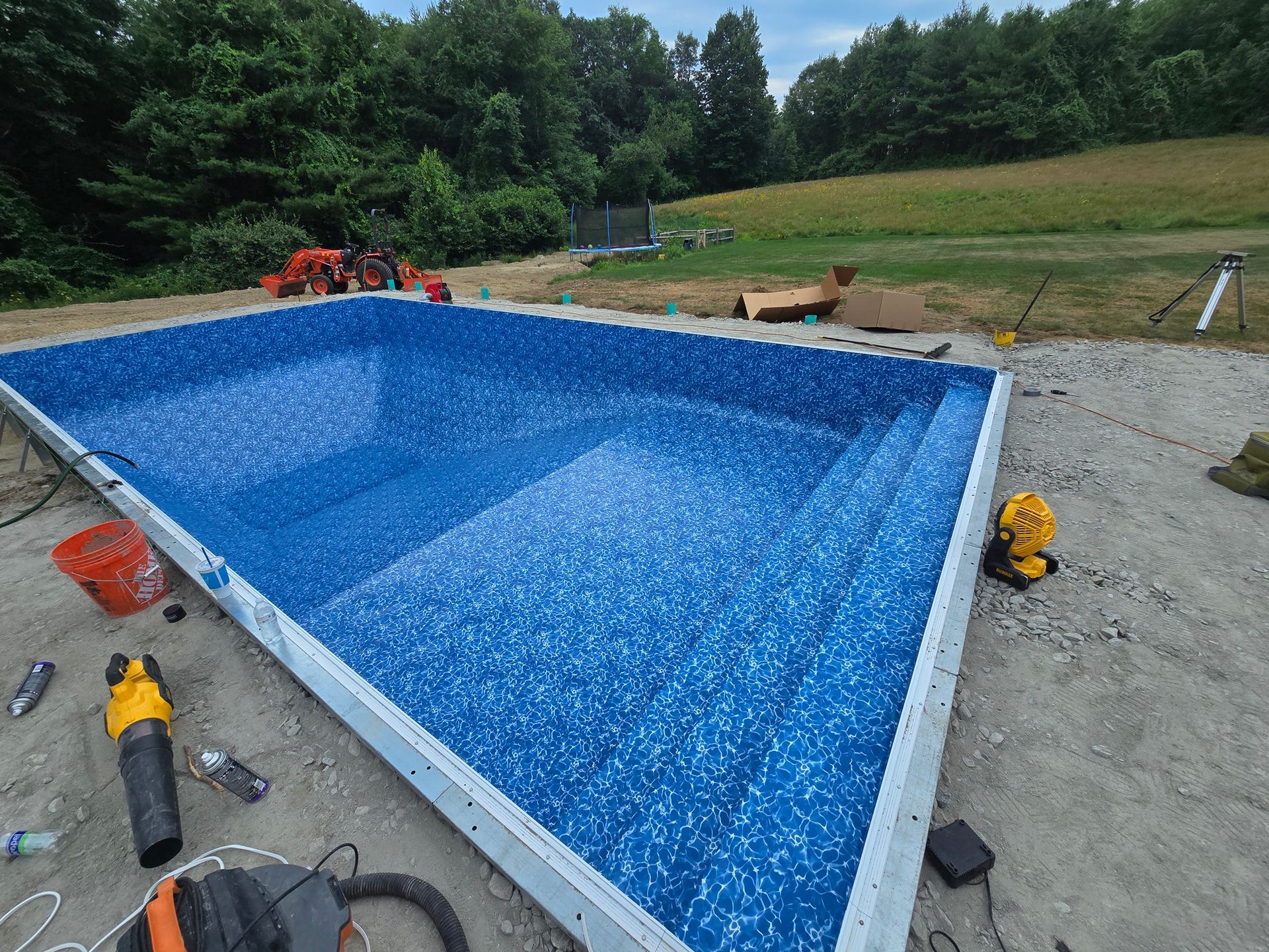 A large swimming pool is being built in a backyard.