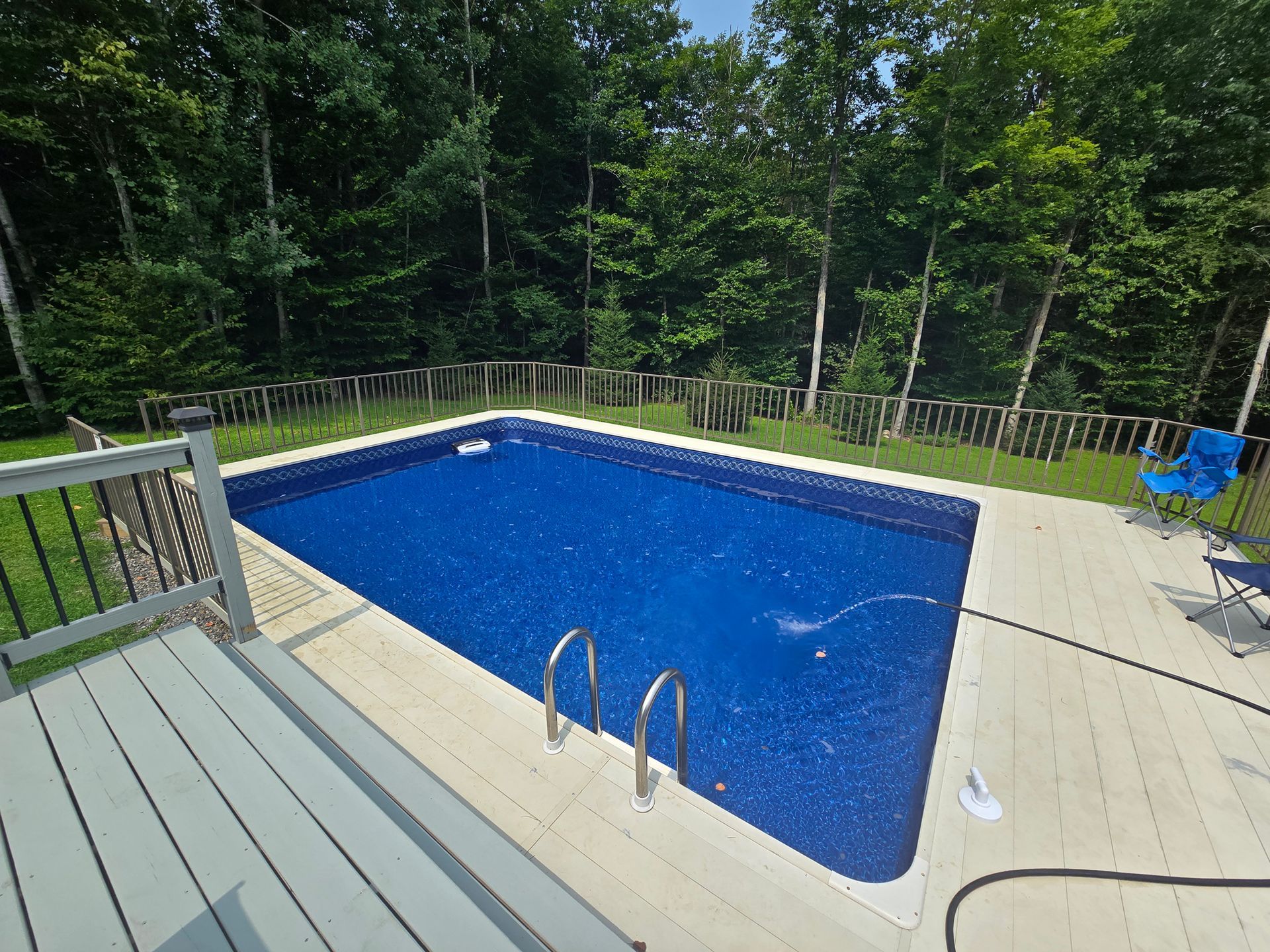 A large swimming pool is surrounded by trees and a deck