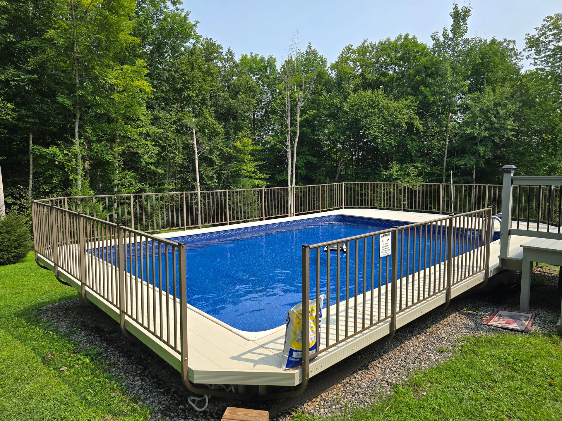 A large swimming pool with a fence around it and trees in the background.