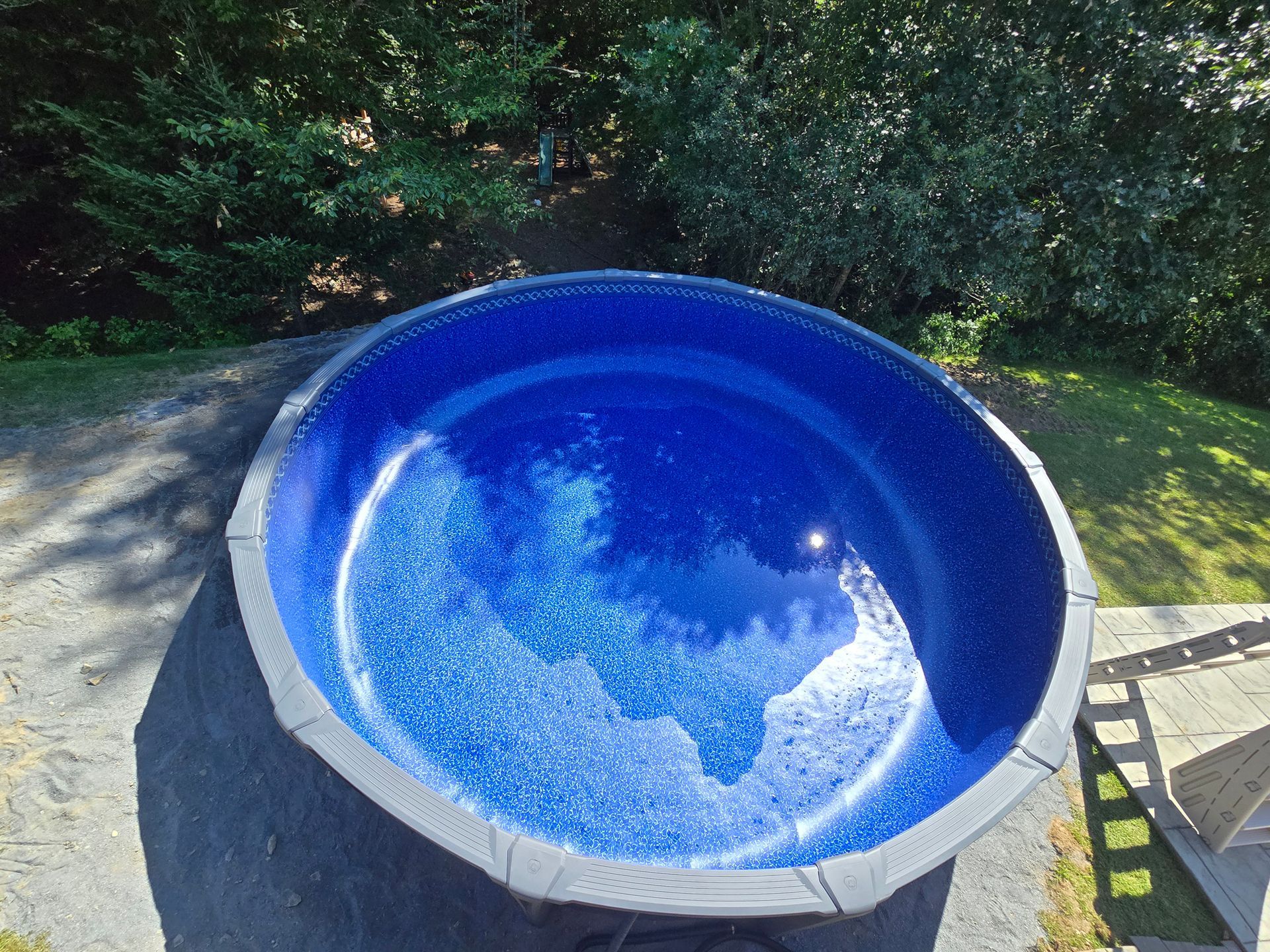 A large blue swimming pool with trees in the background