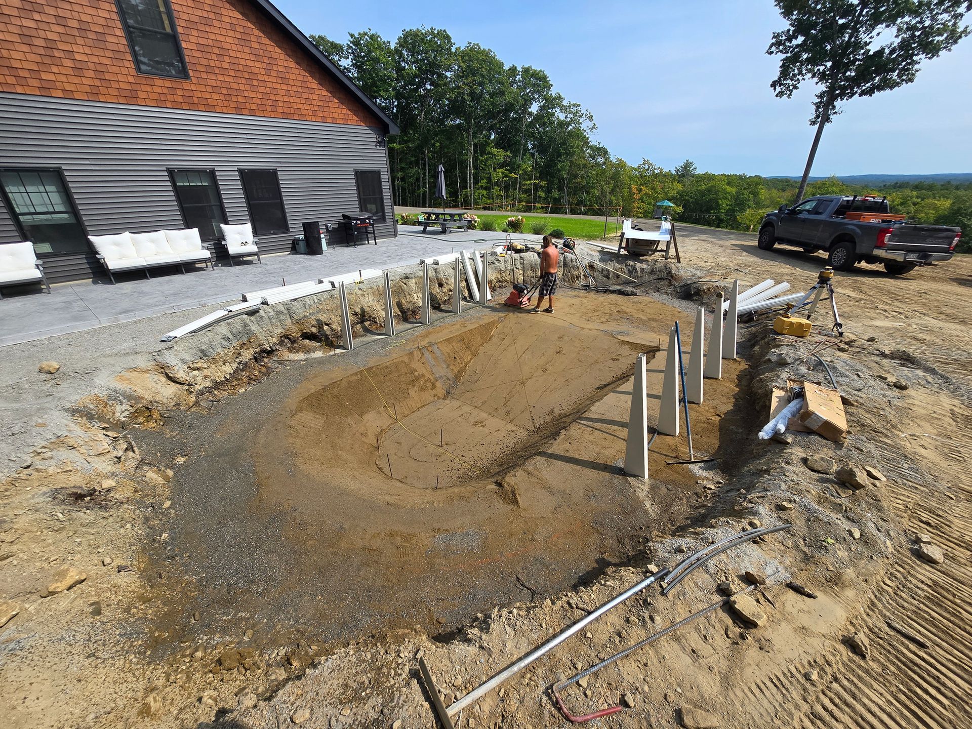 A man is digging a hole in the dirt in front of a house.