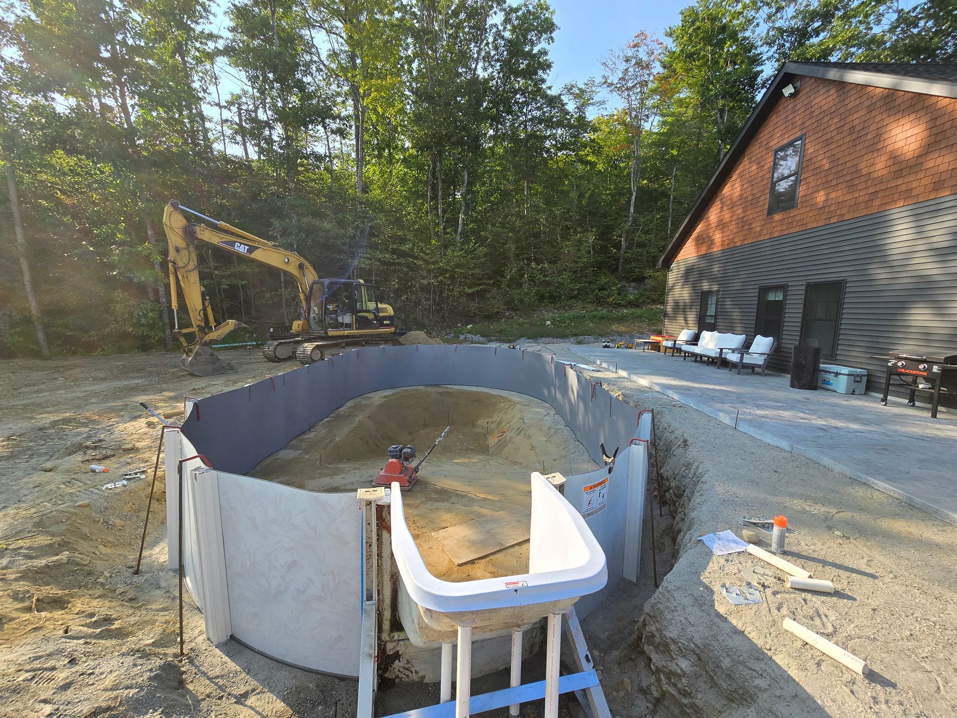A swimming pool is being built in the dirt in front of a brick building.
