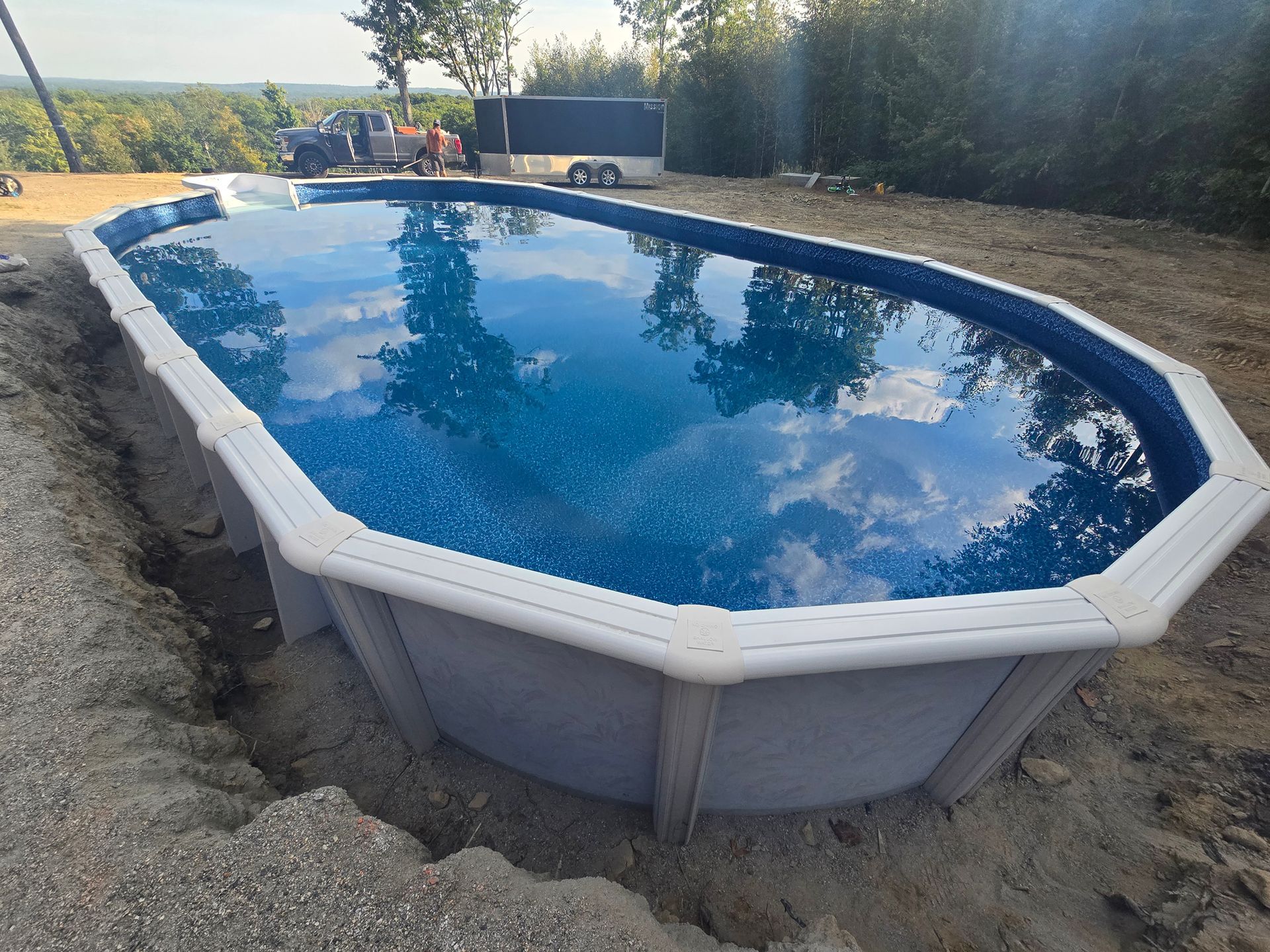 A large swimming pool is sitting on top of a dirt hill.