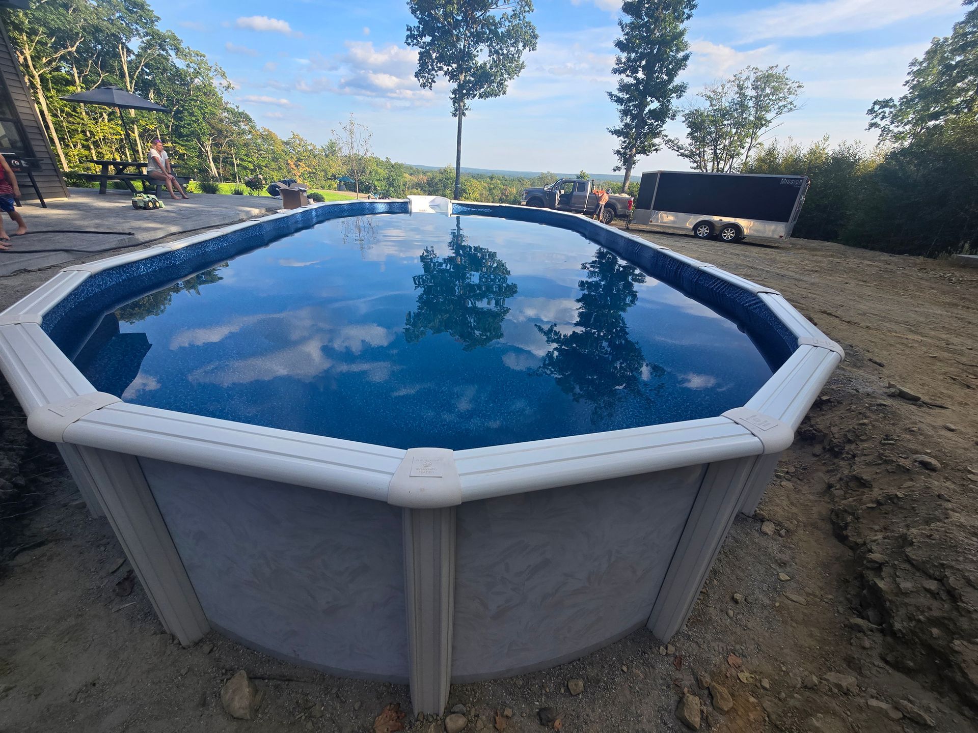 A large swimming pool is sitting on top of a dirt hill.