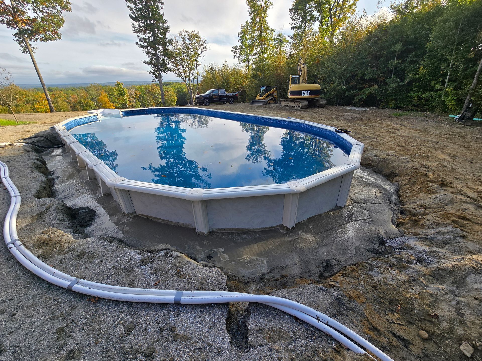 A large swimming pool is being built in a dirt field.