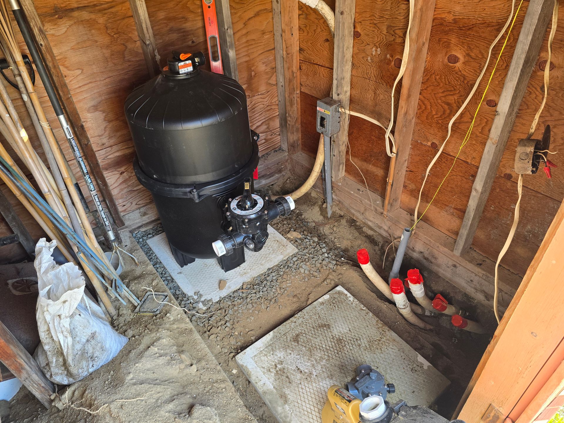 A pool filter is sitting inside of a wooden shed.