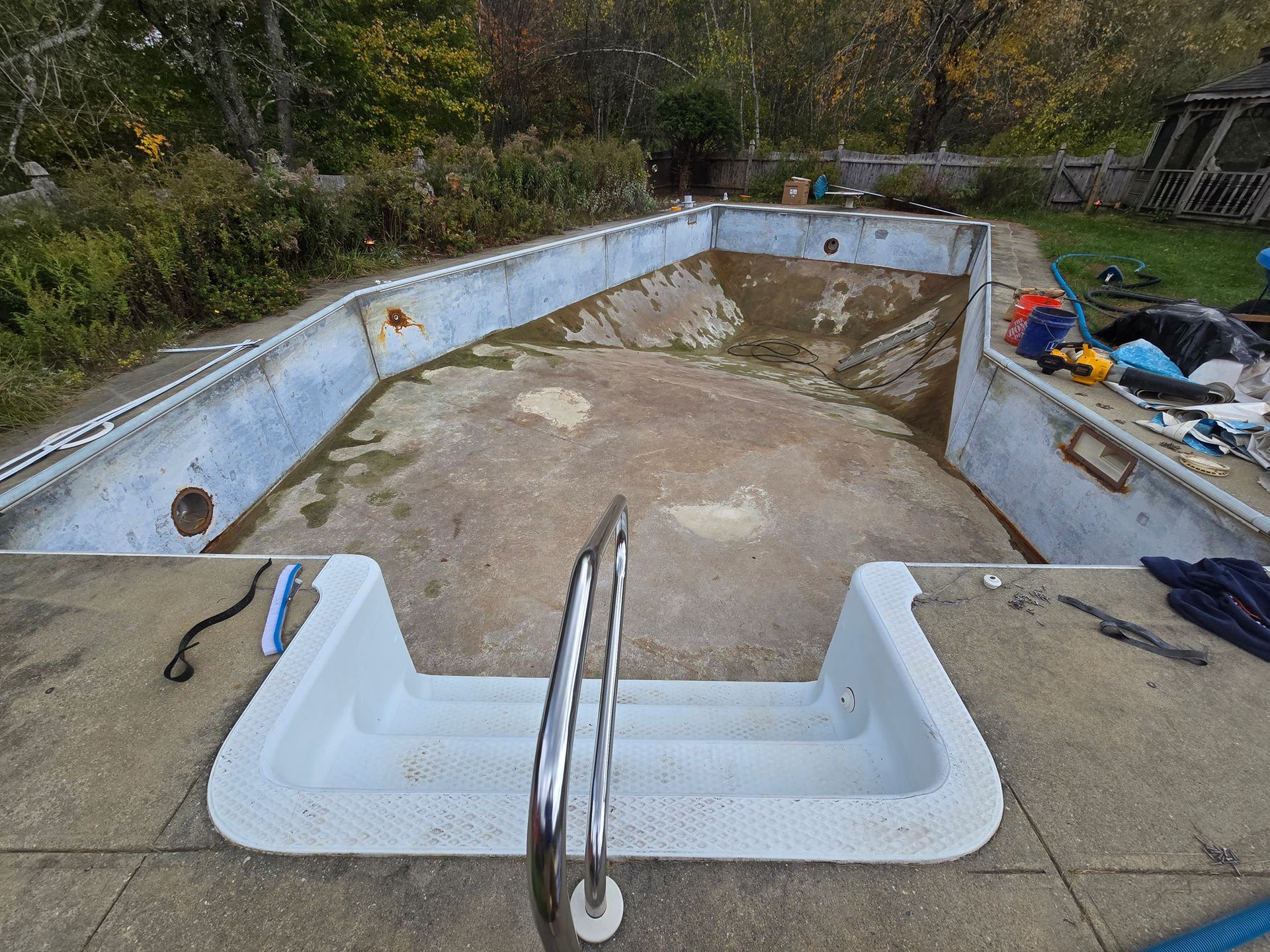 An empty swimming pool is sitting on top of a concrete deck.