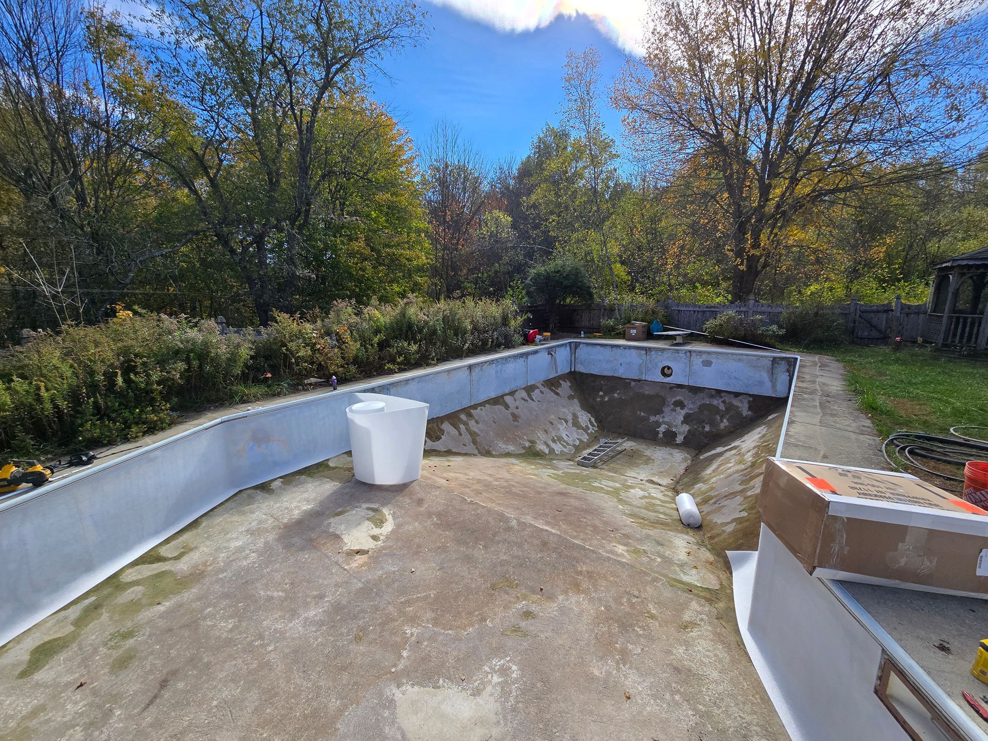 A swimming pool is being remodeled in a backyard on a sunny day.