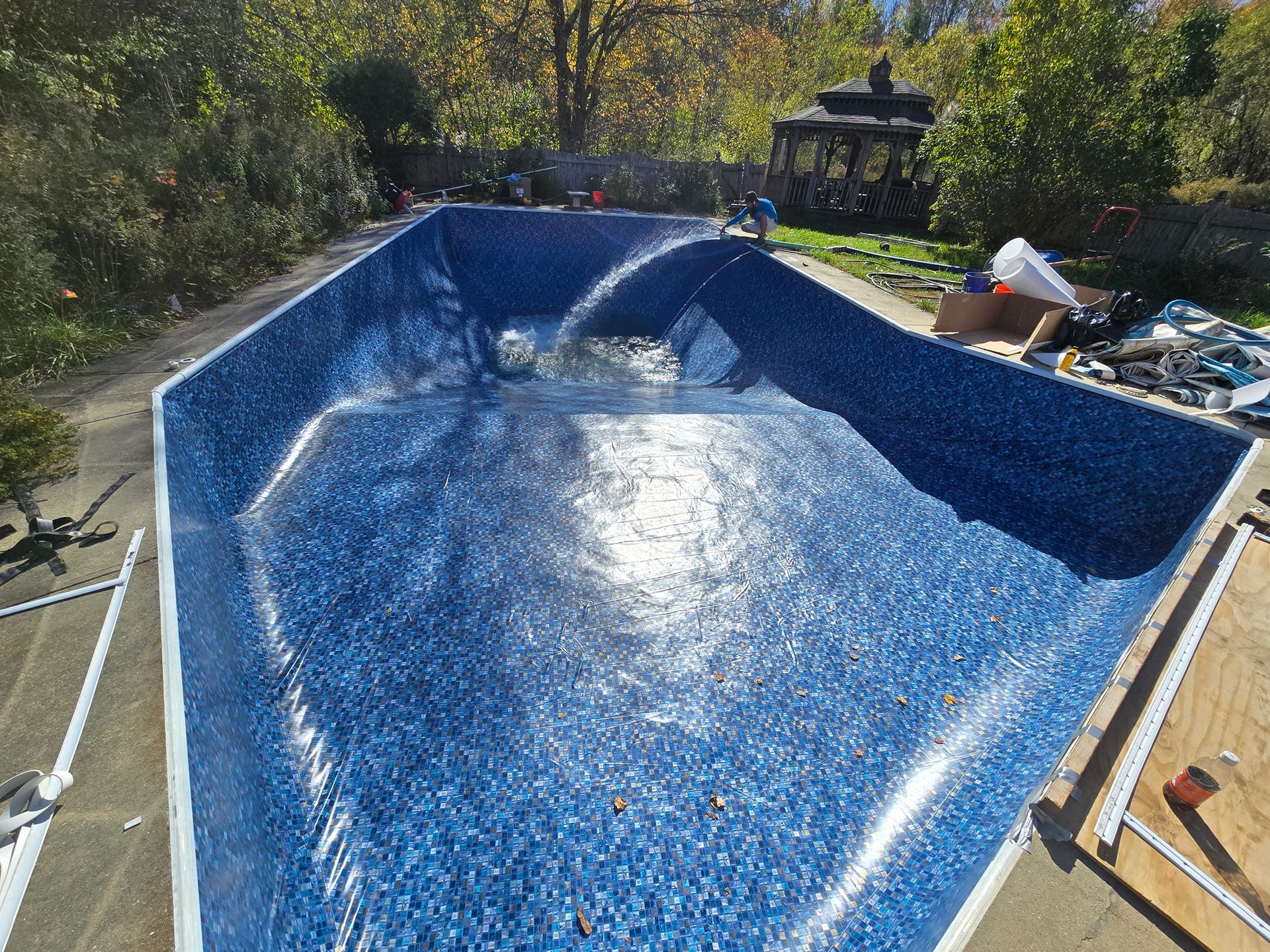 A large blue swimming pool is being built in a backyard.
