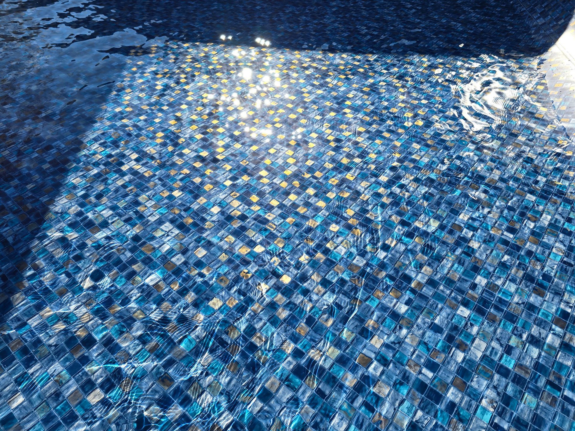 A close up of a swimming pool with blue and gold tiles.