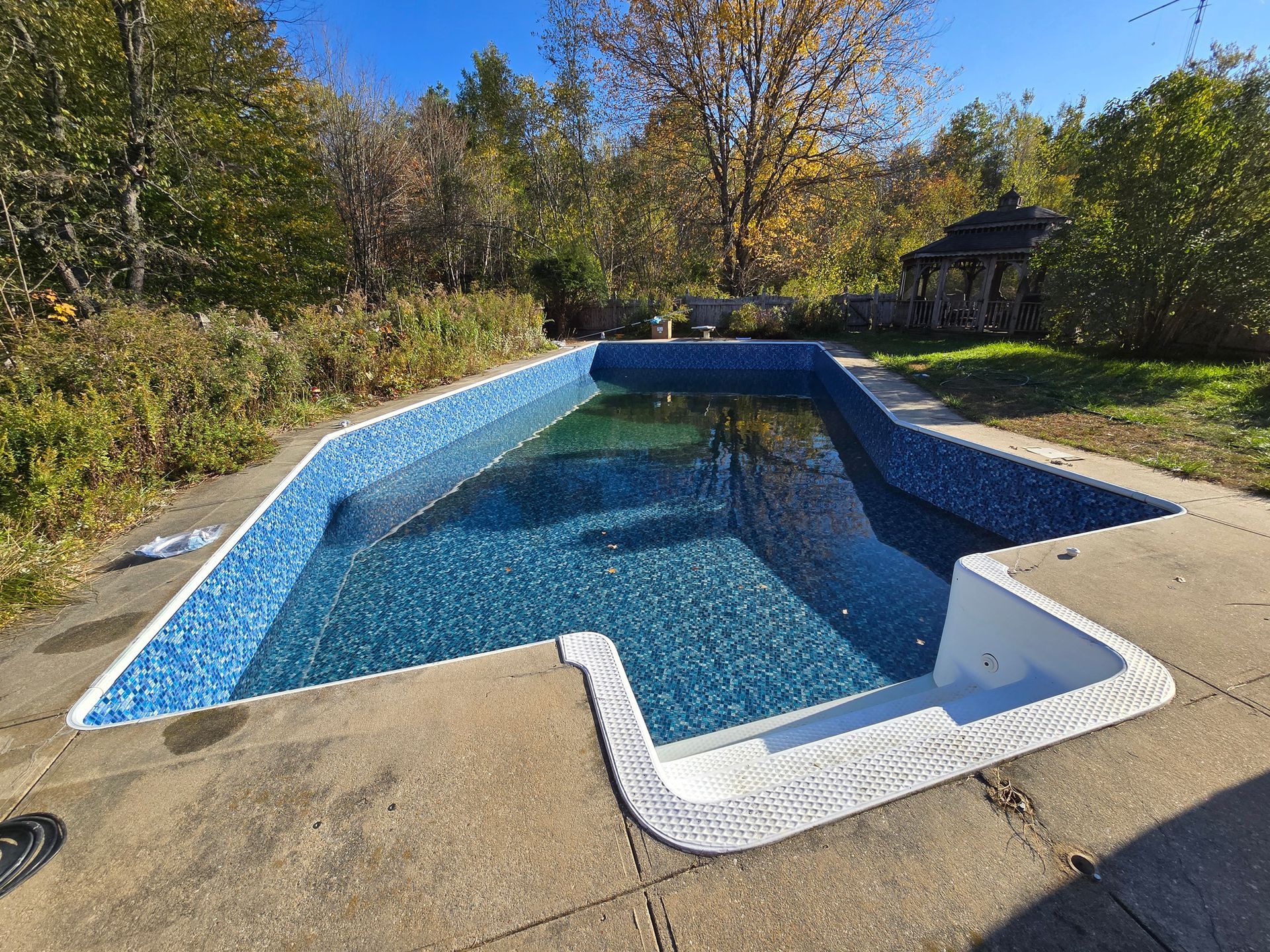 A large swimming pool is sitting on top of a concrete patio.
