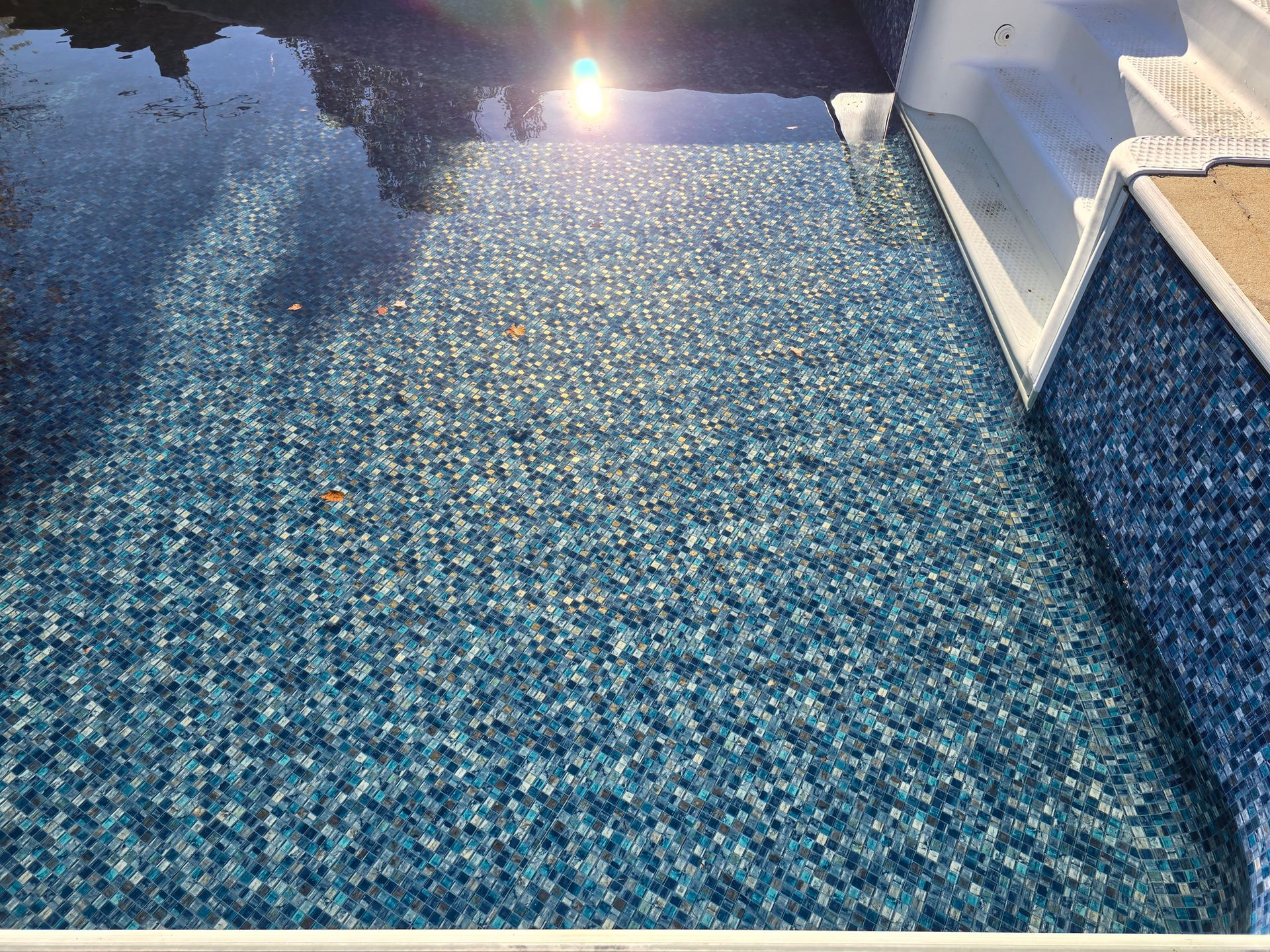 A swimming pool with stairs leading up to it and a blue tile floor.