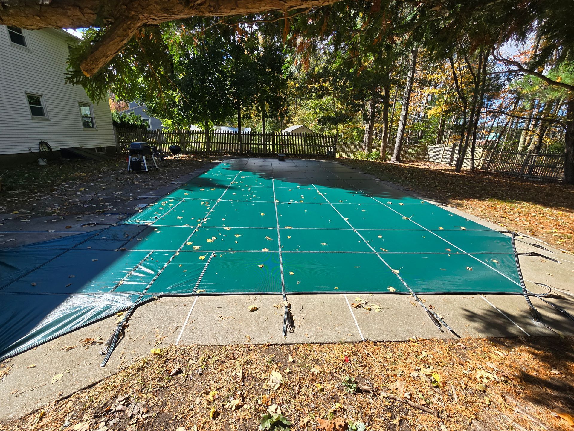 A green pool cover is sitting on top of a concrete surface.