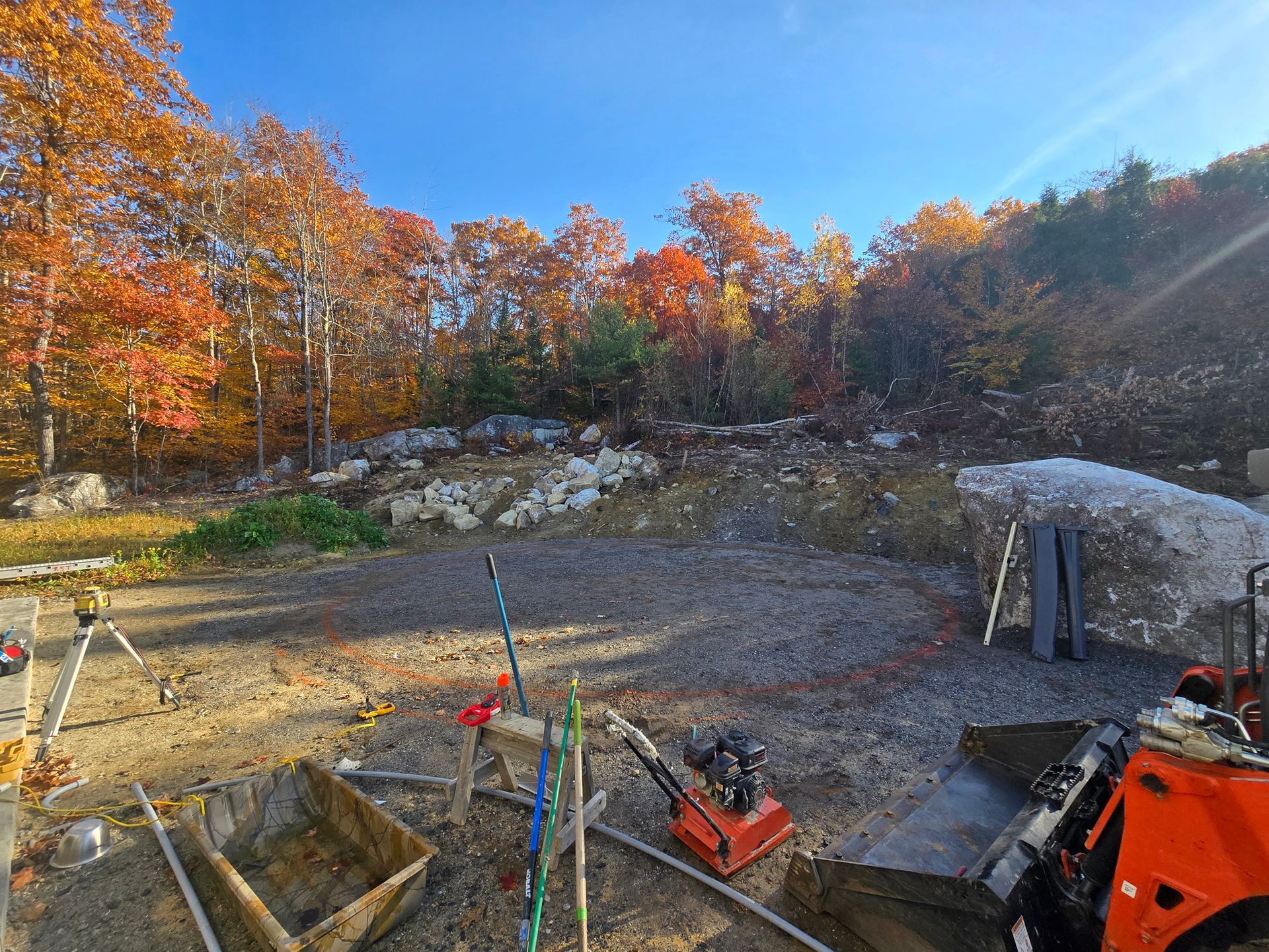 A construction site with trees in the background and a tractor in the foreground.