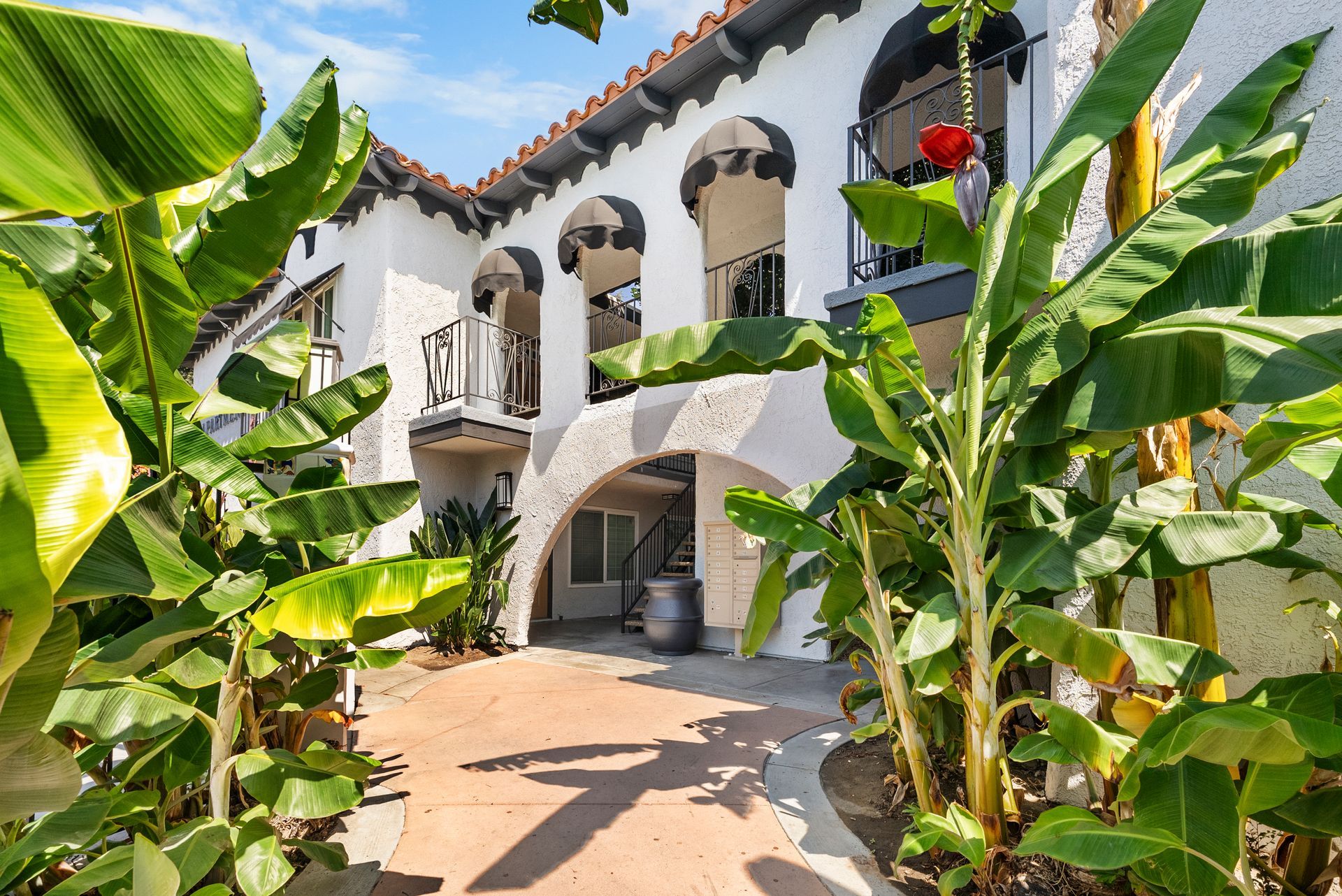 bulding exterior with awnings surrounded by lush plants