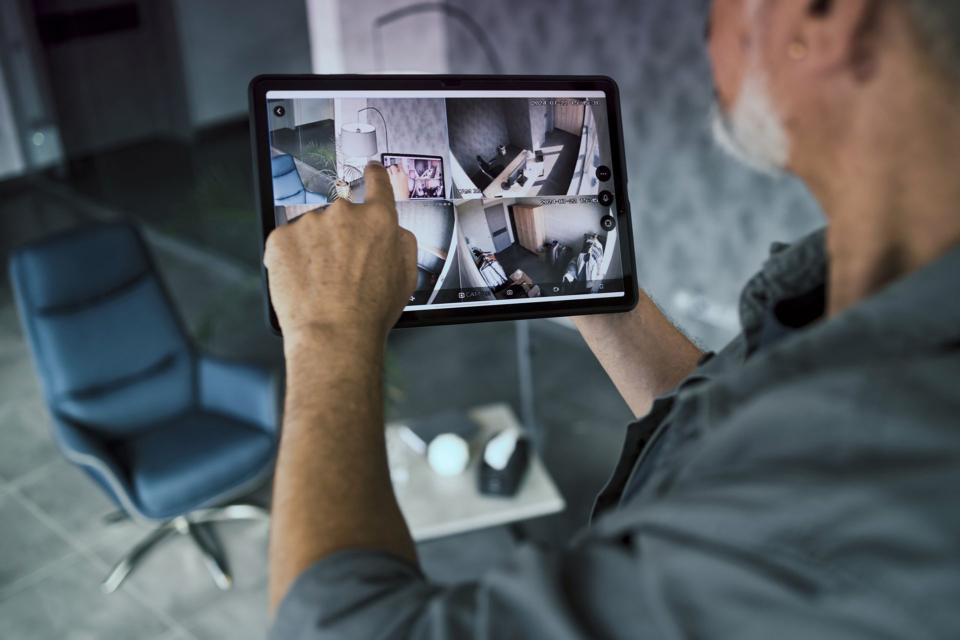 Man using tablet to view security camera footage of home interior.