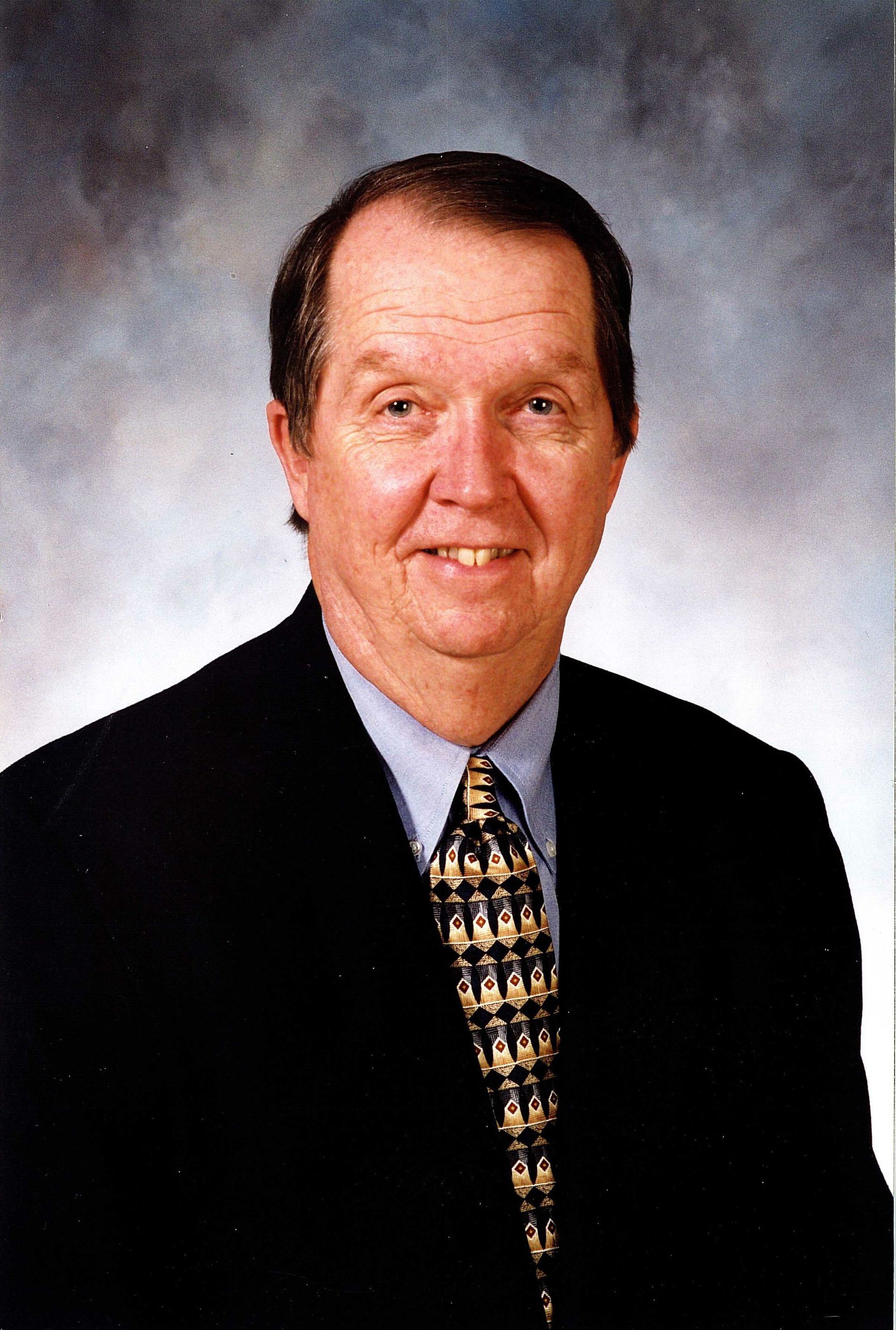 A man in a suit and tie is smiling for the camera