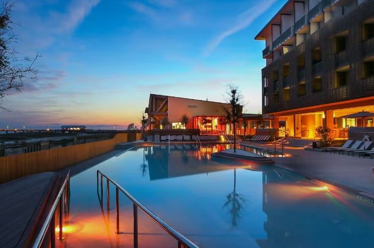 A large swimming pool in front of a hotel at sunset.