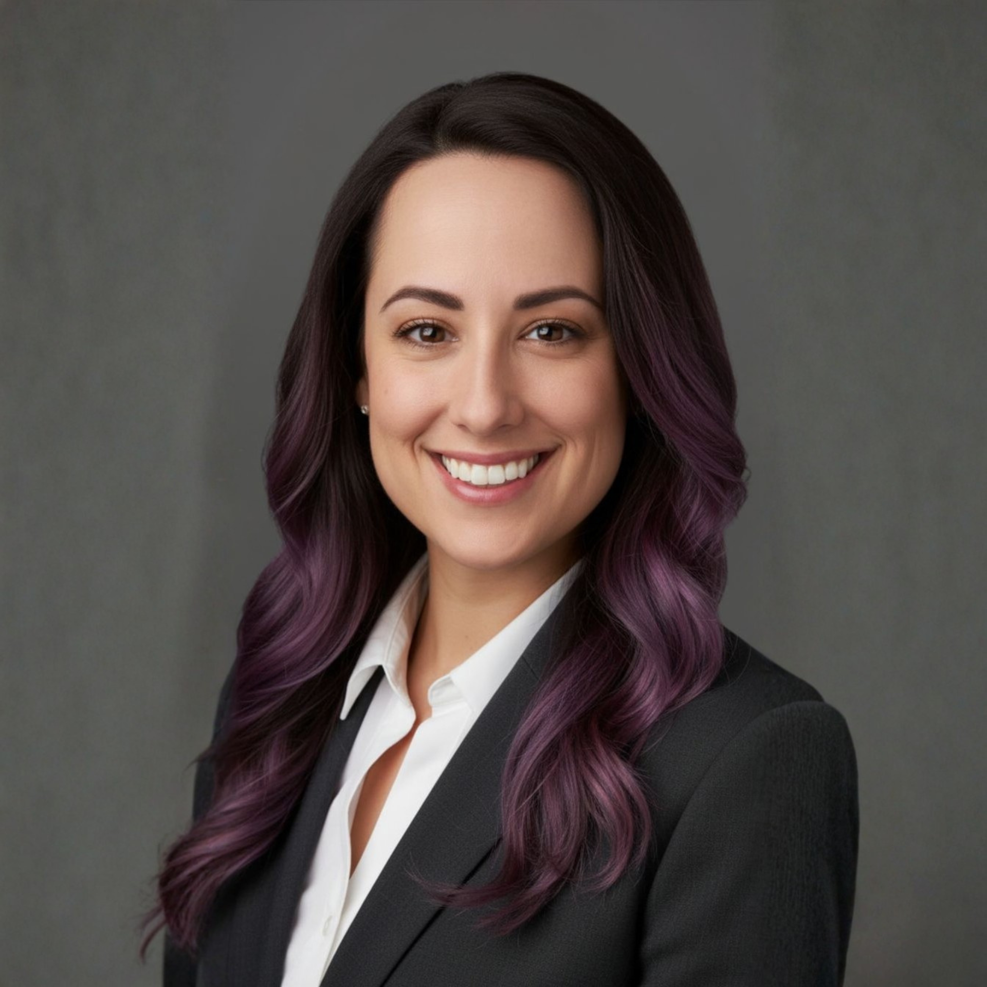 Woman with auburn wavy hair and a smile, wearing a black top.