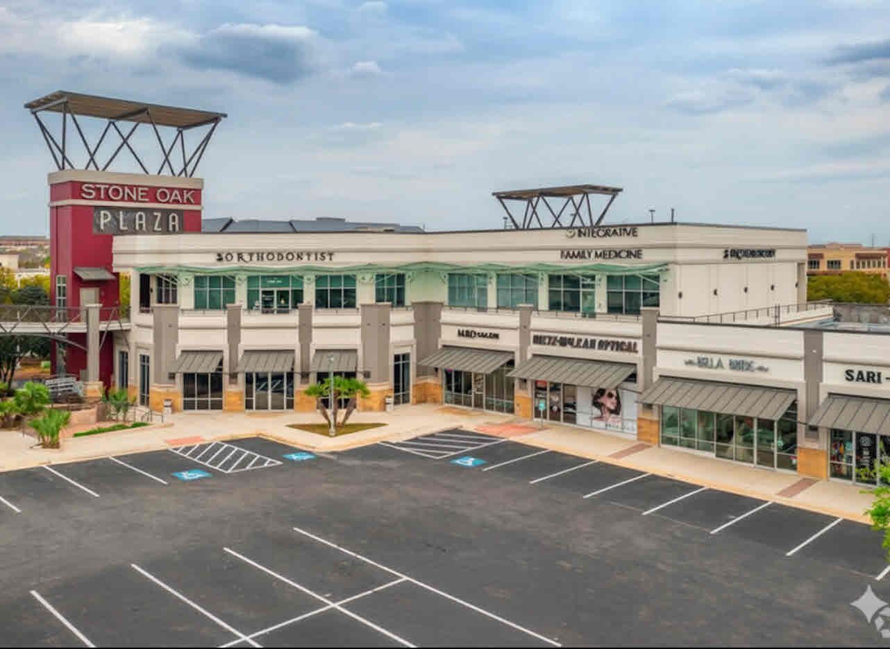 Retail plaza with parking, businesses include dental office and hair salon.