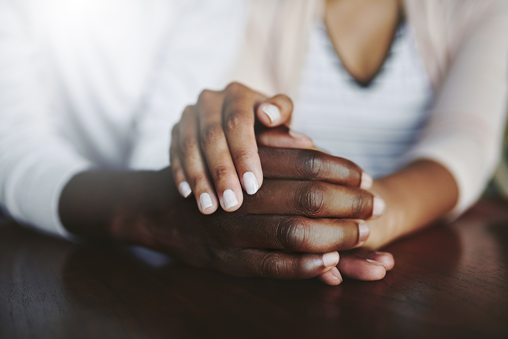 A group of people are sitting in a circle holding hands and talking to each other.