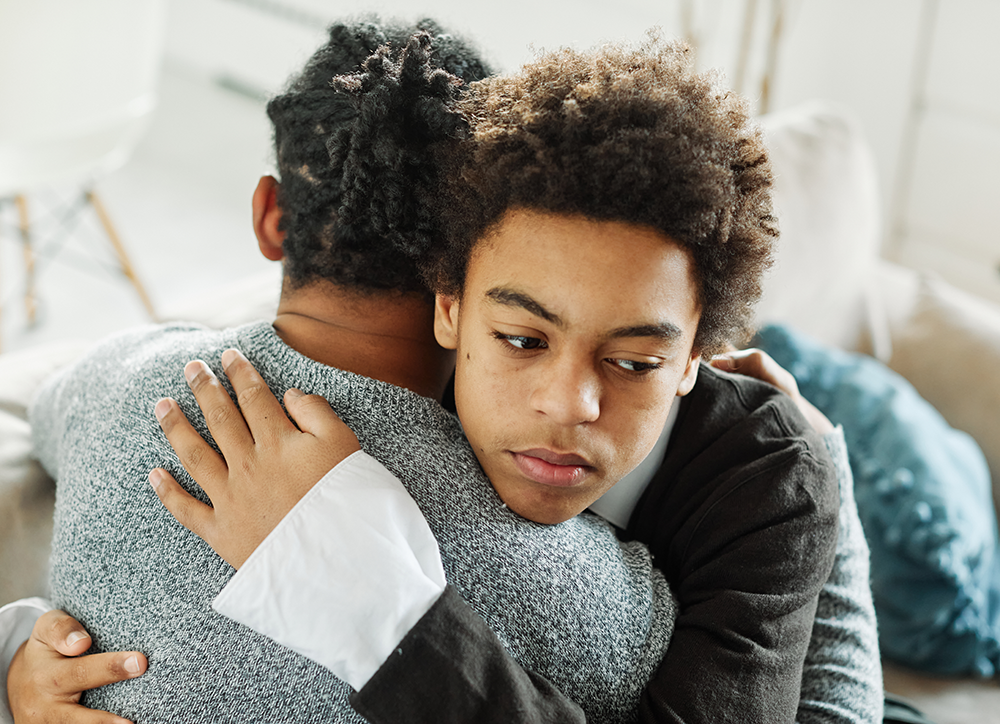 A young woman is sitting on a window sill looking out the window.