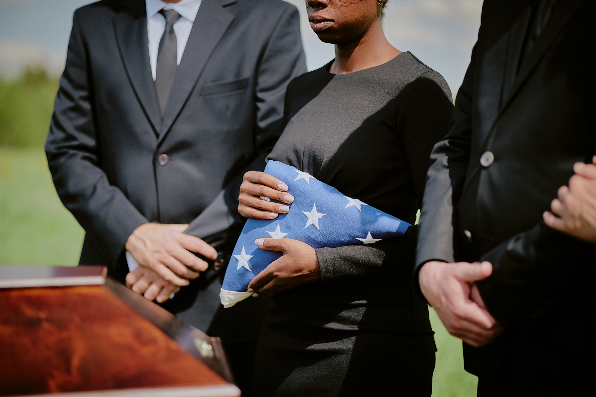 A group of people are standing around a coffin at a funeral.