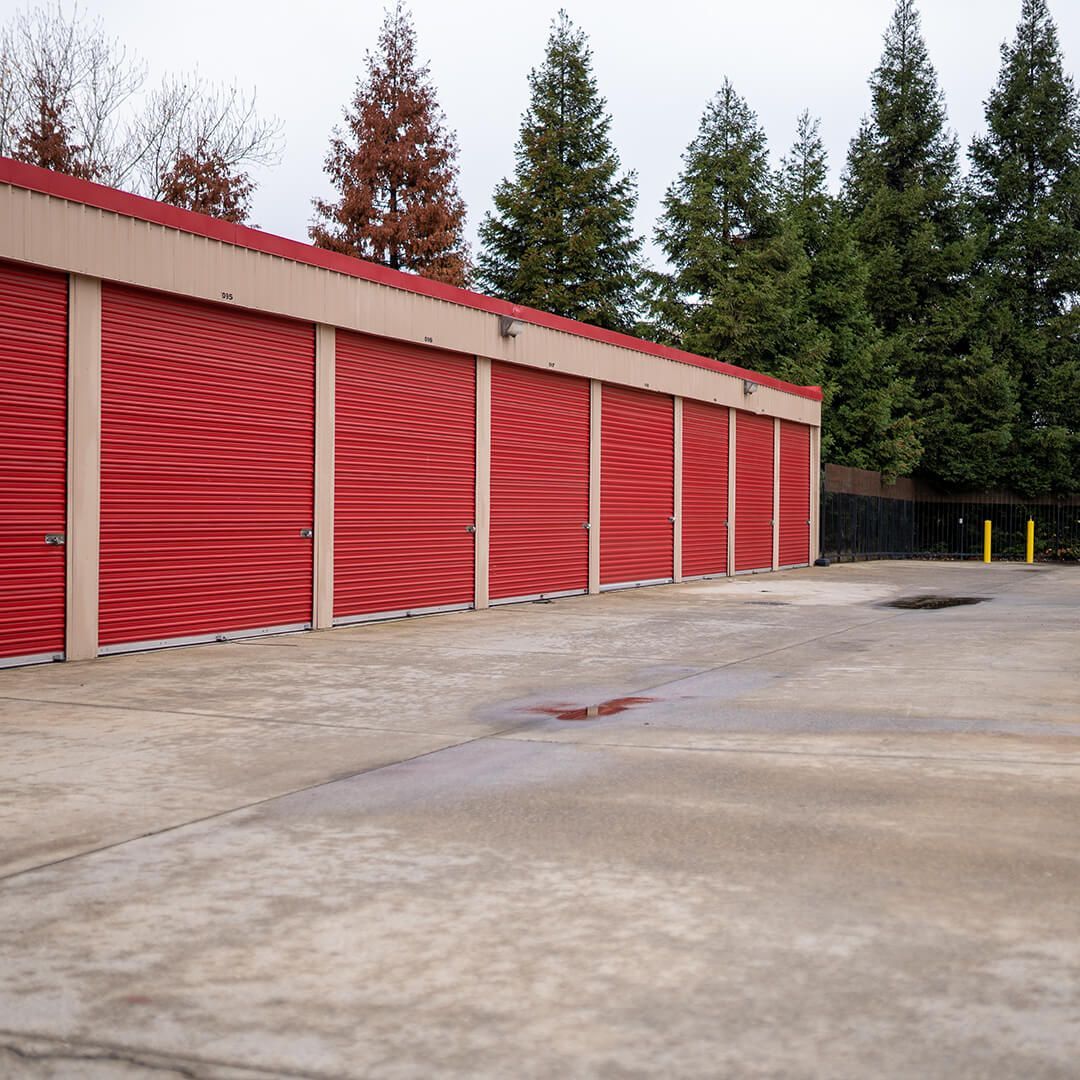 a row of red storage units with a few trees in the background