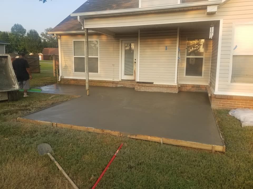 Newly poured concrete patio next to a house with a person standing nearby.